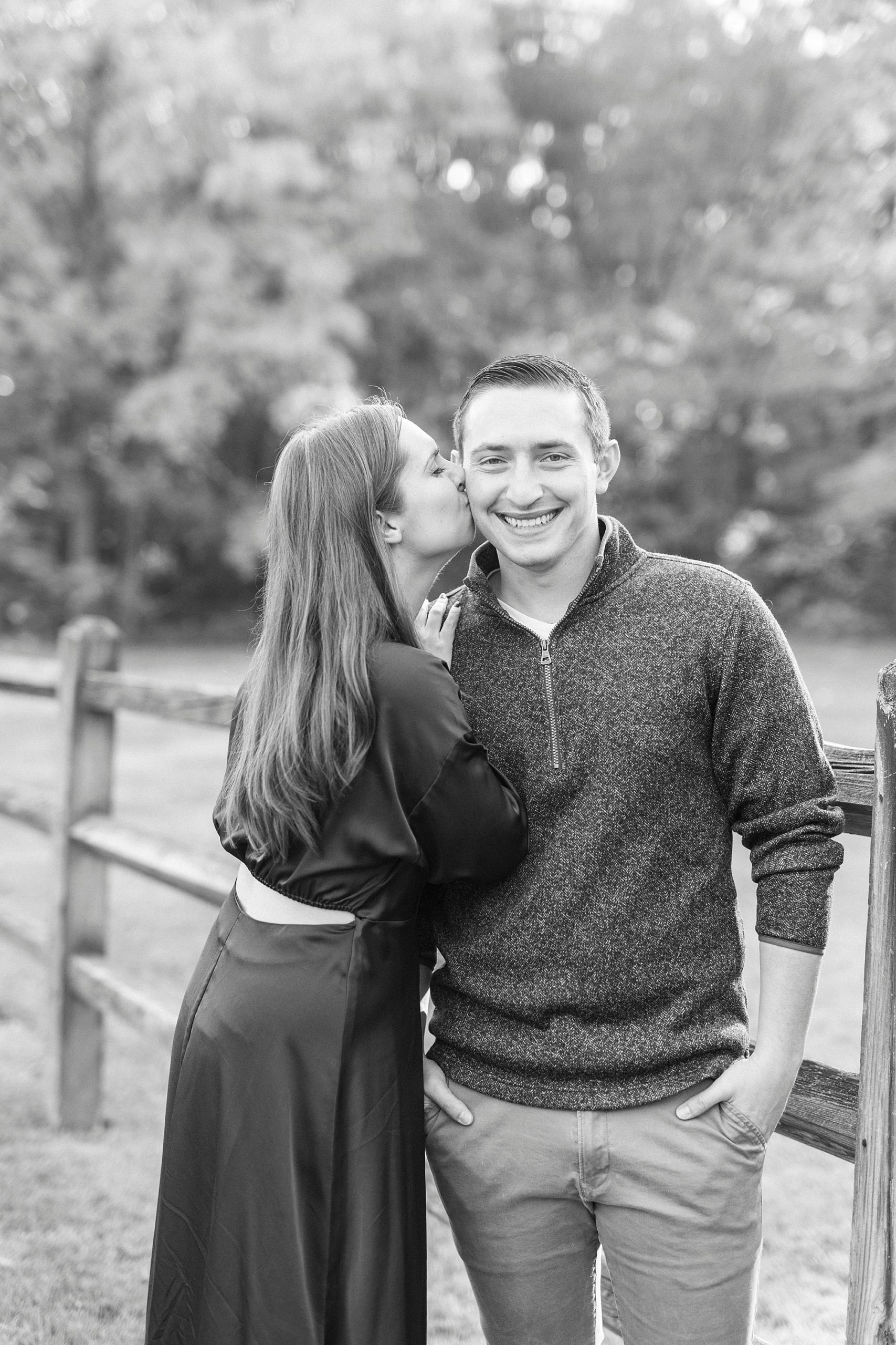 bride kisses groom's cheek along wooden fence at Latta Nature Preserve