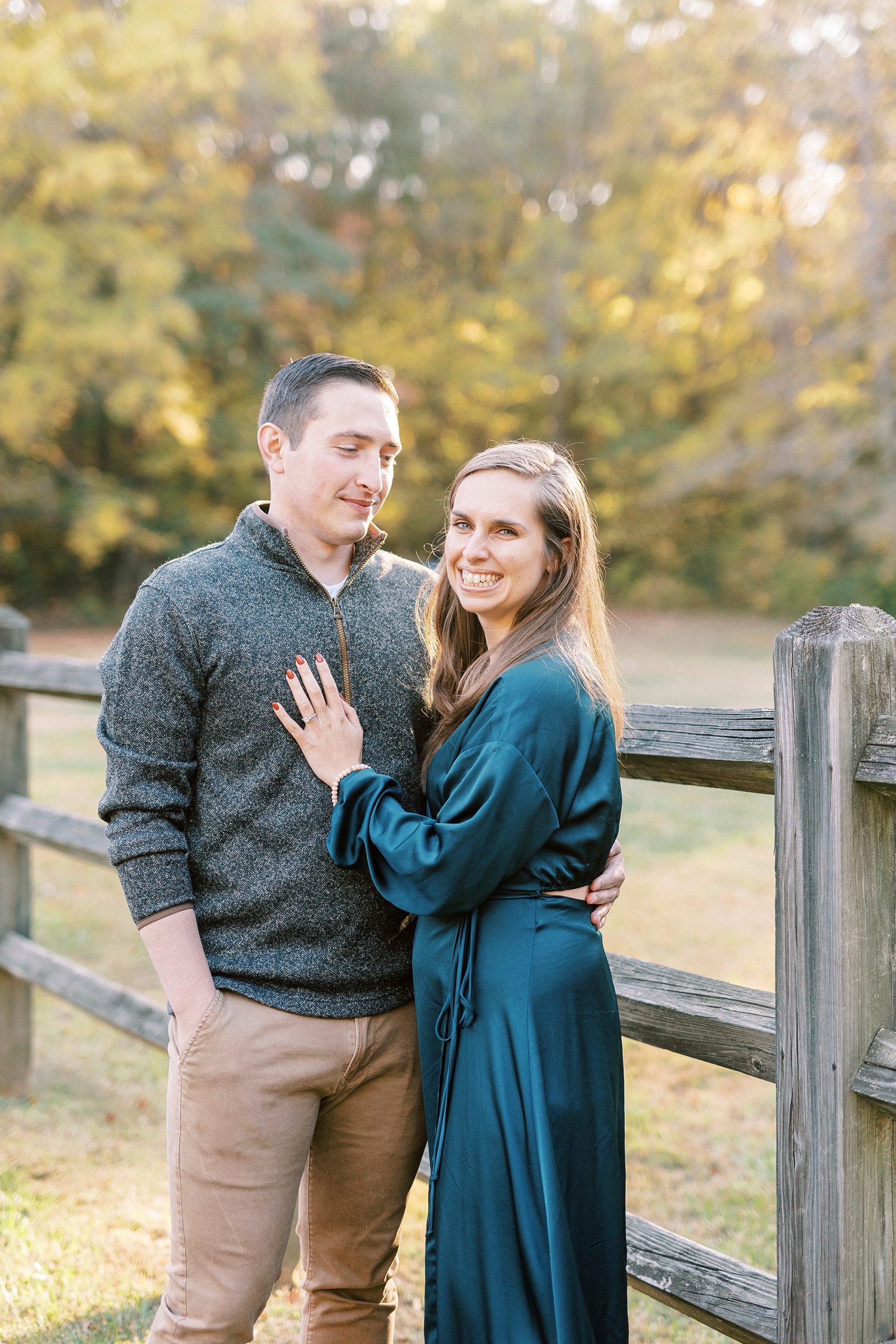 bride in teal dress hugs fiancee during fall Latta Nature Preserve engagement session