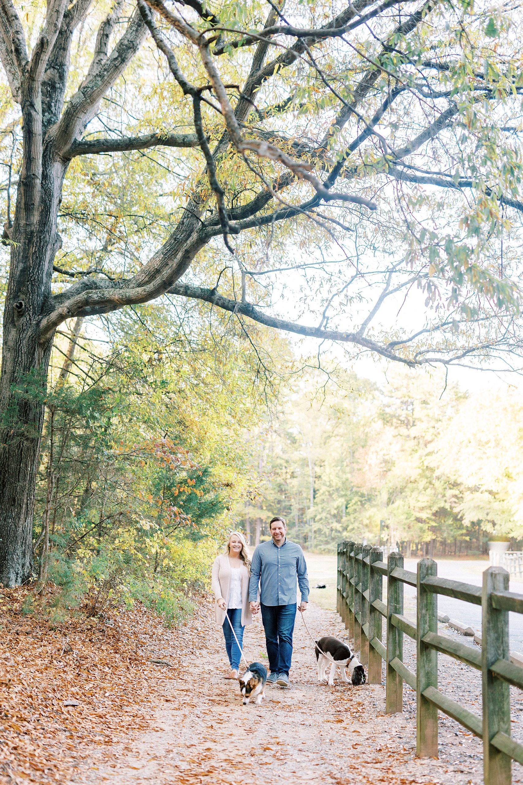 bride and groom hold hands walking by wooden fence in Latta Nature Preserve