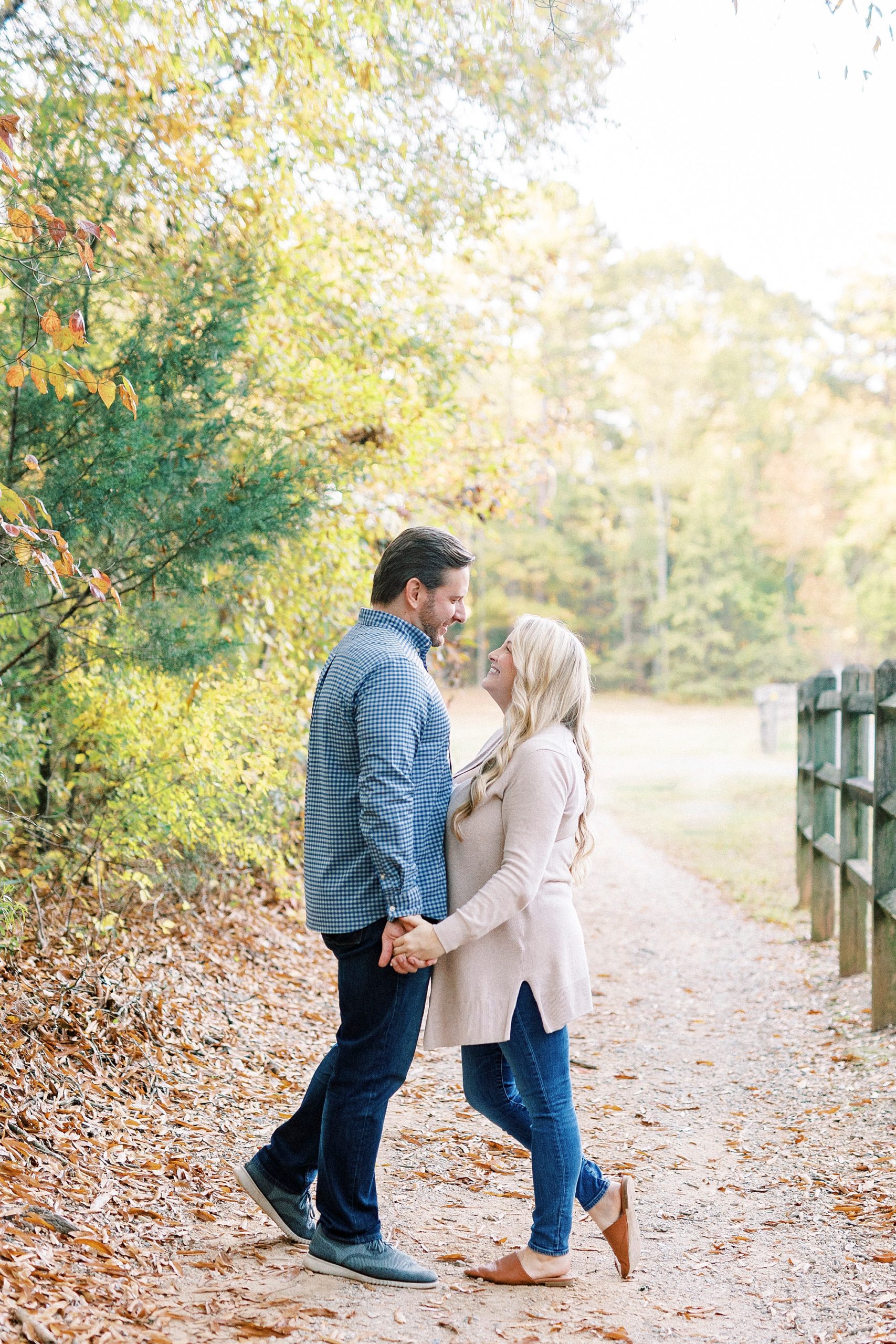 bride and groom hold hands by wooden fence at Latta Nature Preserve