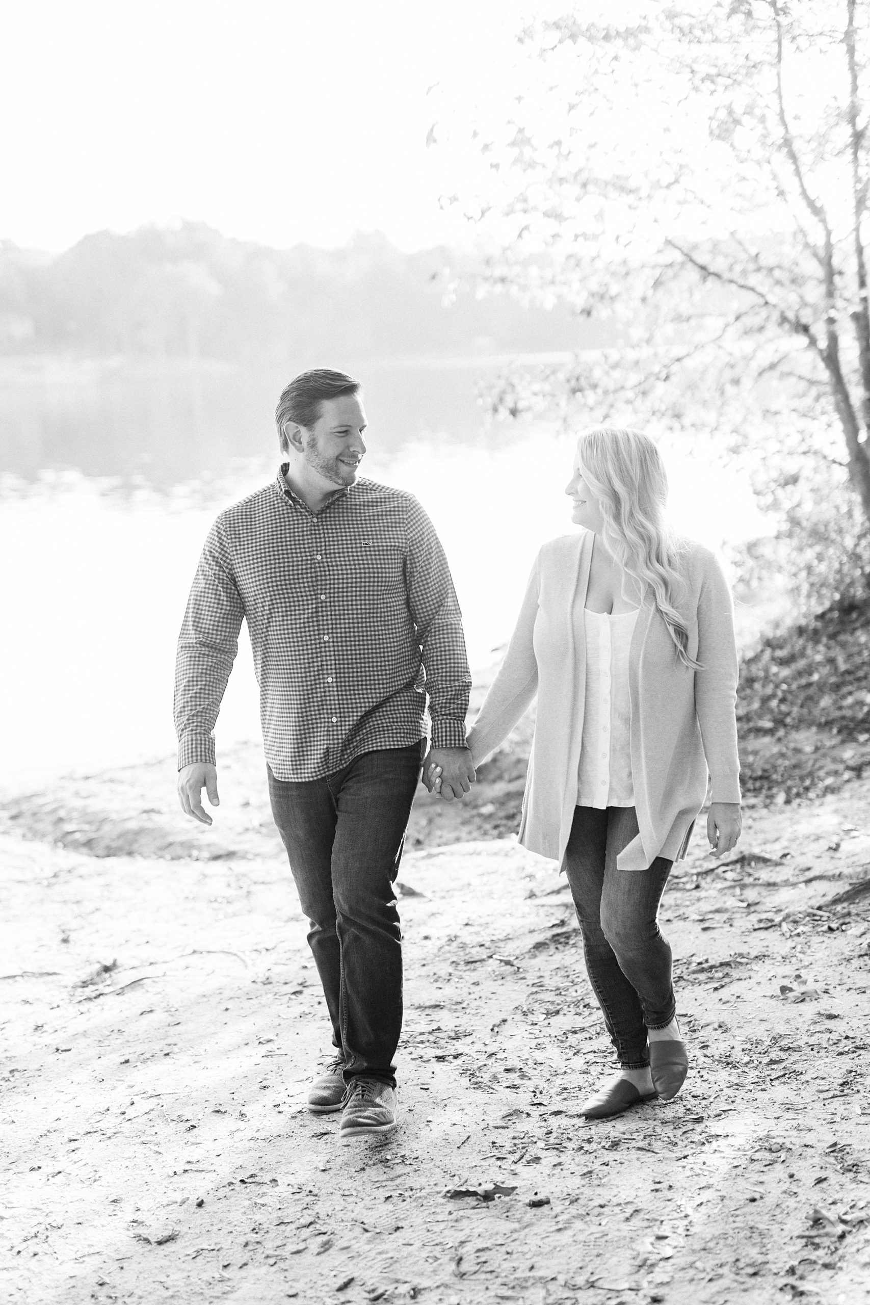 engaged couple holds hands walking through leaves in Mecklenburg County