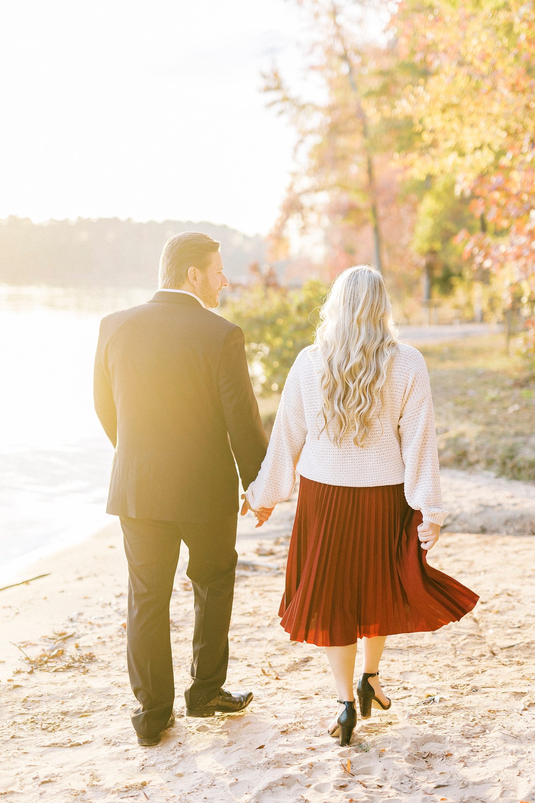 engaged couple holds hands walking along beach at Latta Nature Preserve