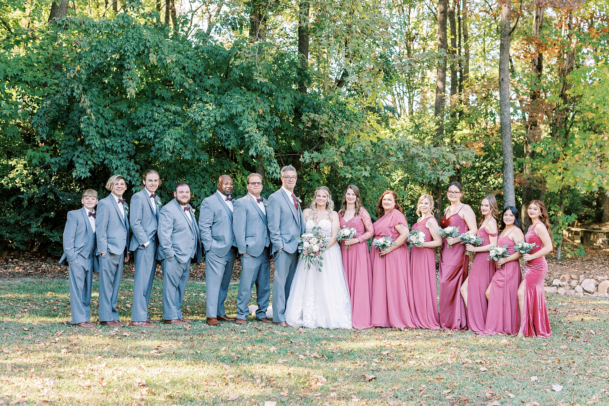 bride and groom cheer with wedding party posing around them