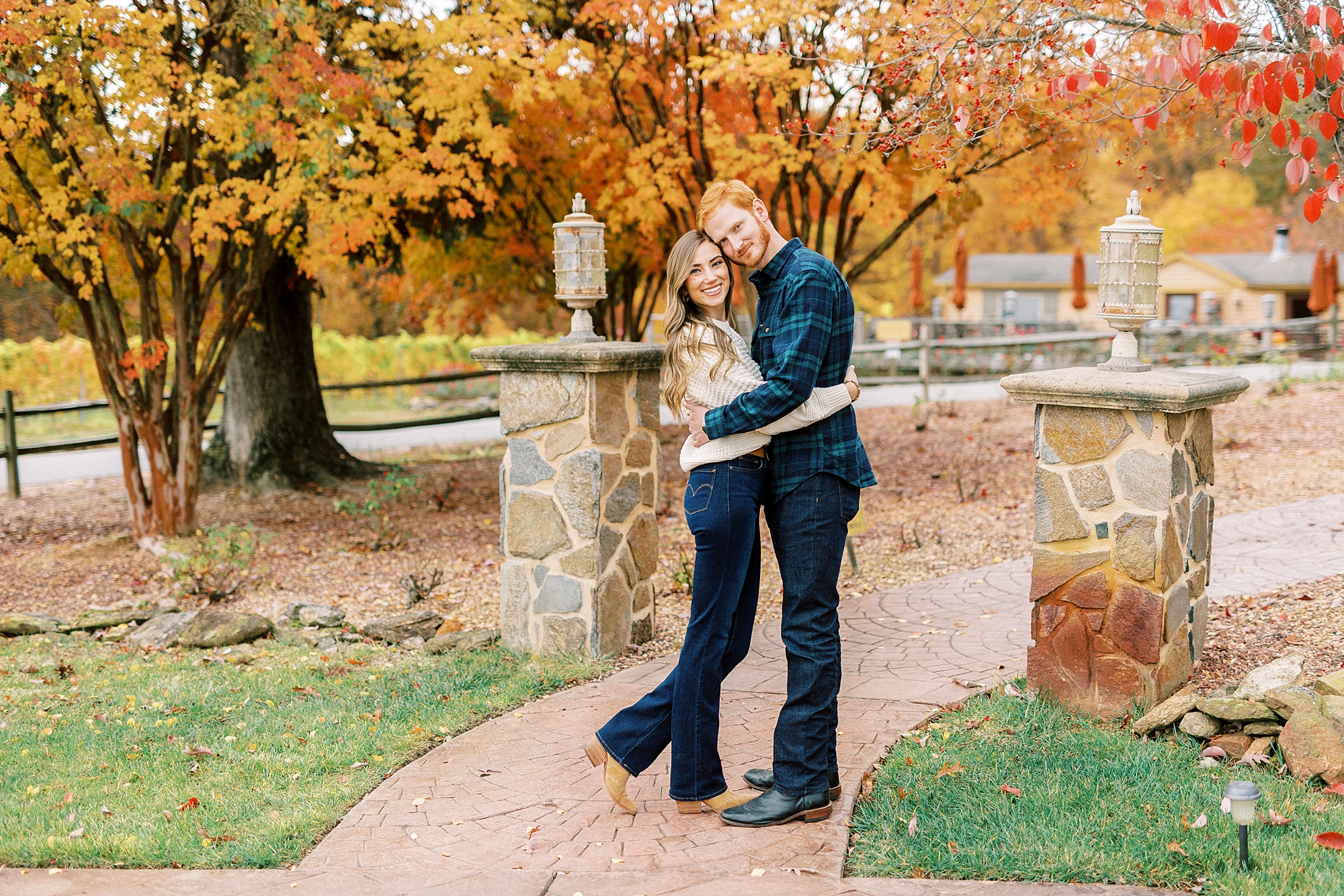 engaged couple hugs outside stone gate at Raffaldini Vineyards