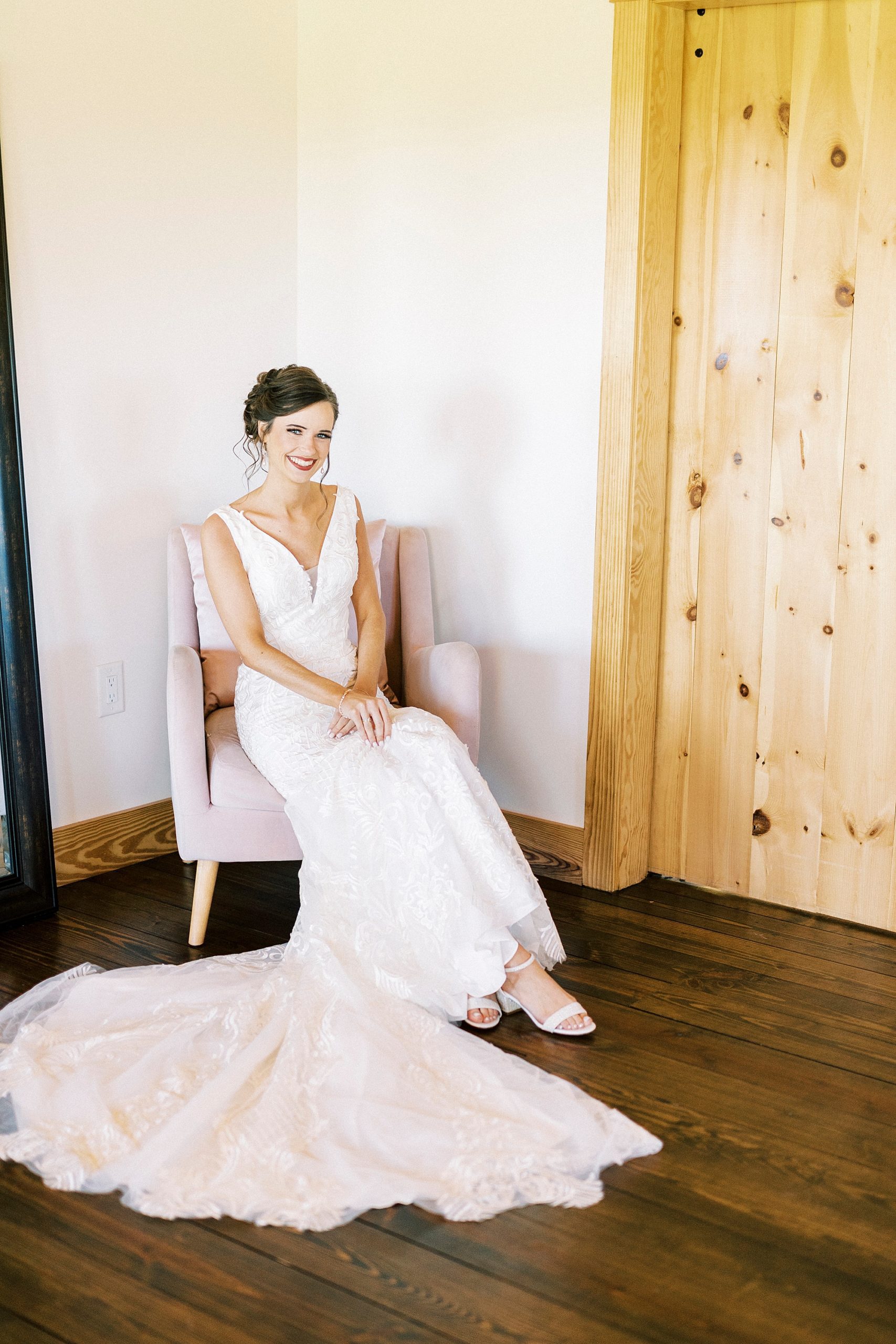 bride sits in wedding gown by wooden door at Chickadee Hill Farms