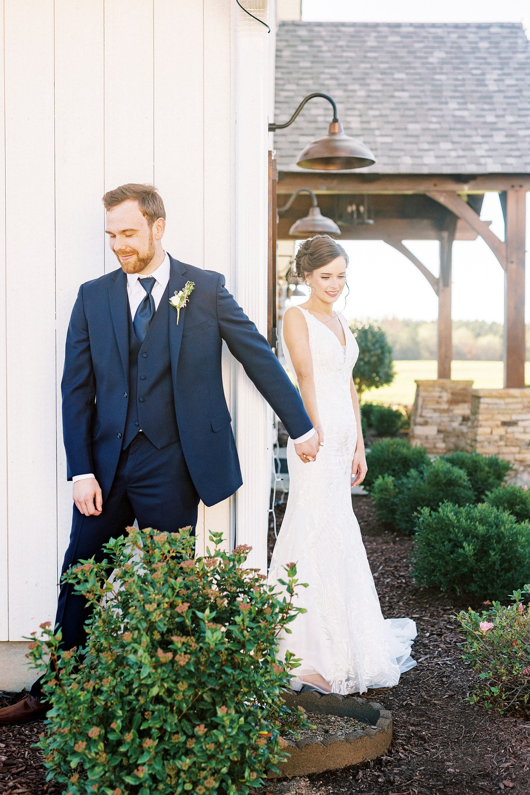 bride and groom hold hands around corner at Chickadee Hill Farms