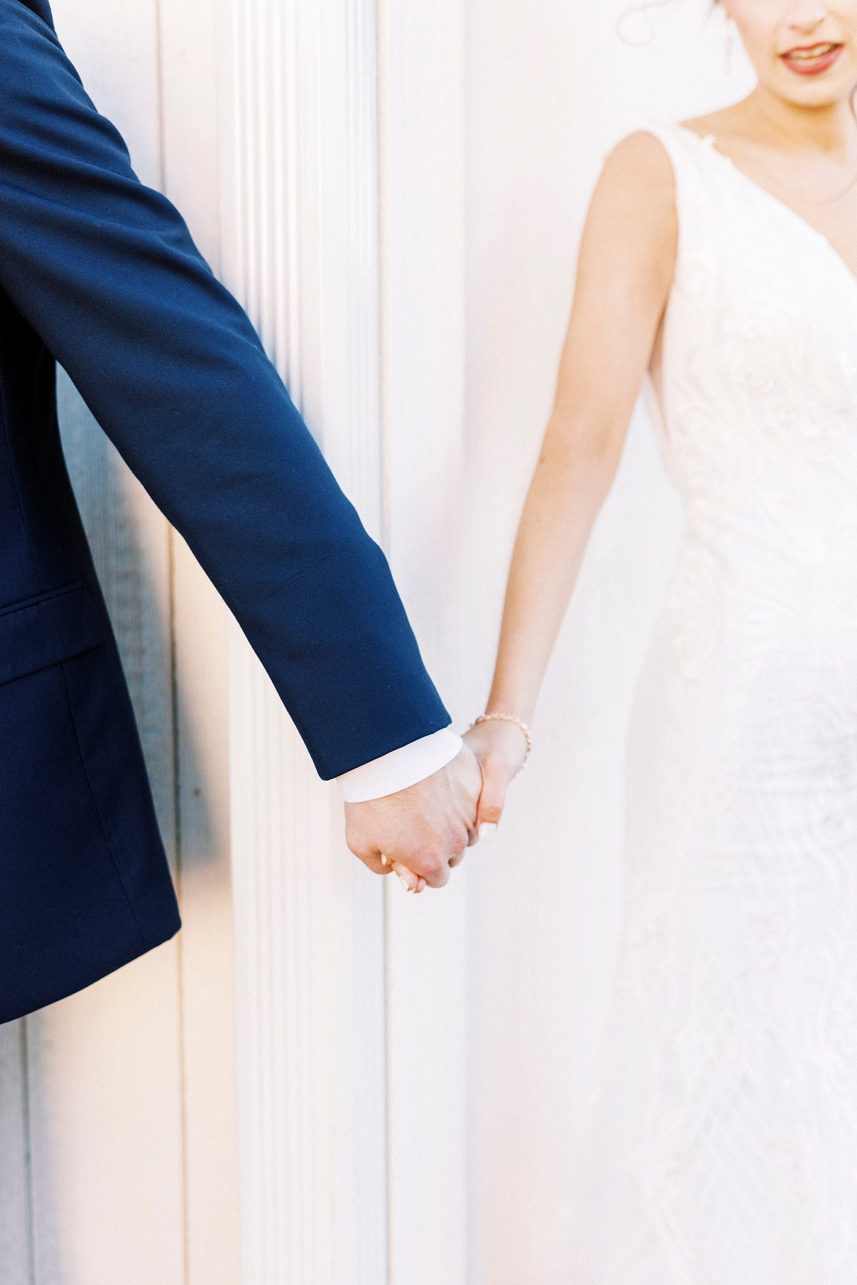 bride and groom hold hands during first touch around corner of barn at Chickadee Hill Farms