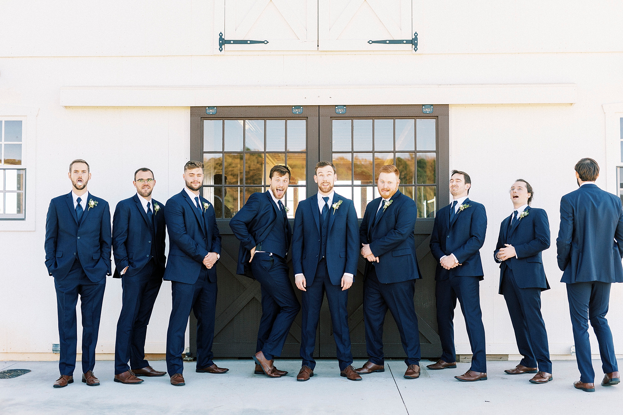 groomsmen laugh during photo with groom in navy suits 