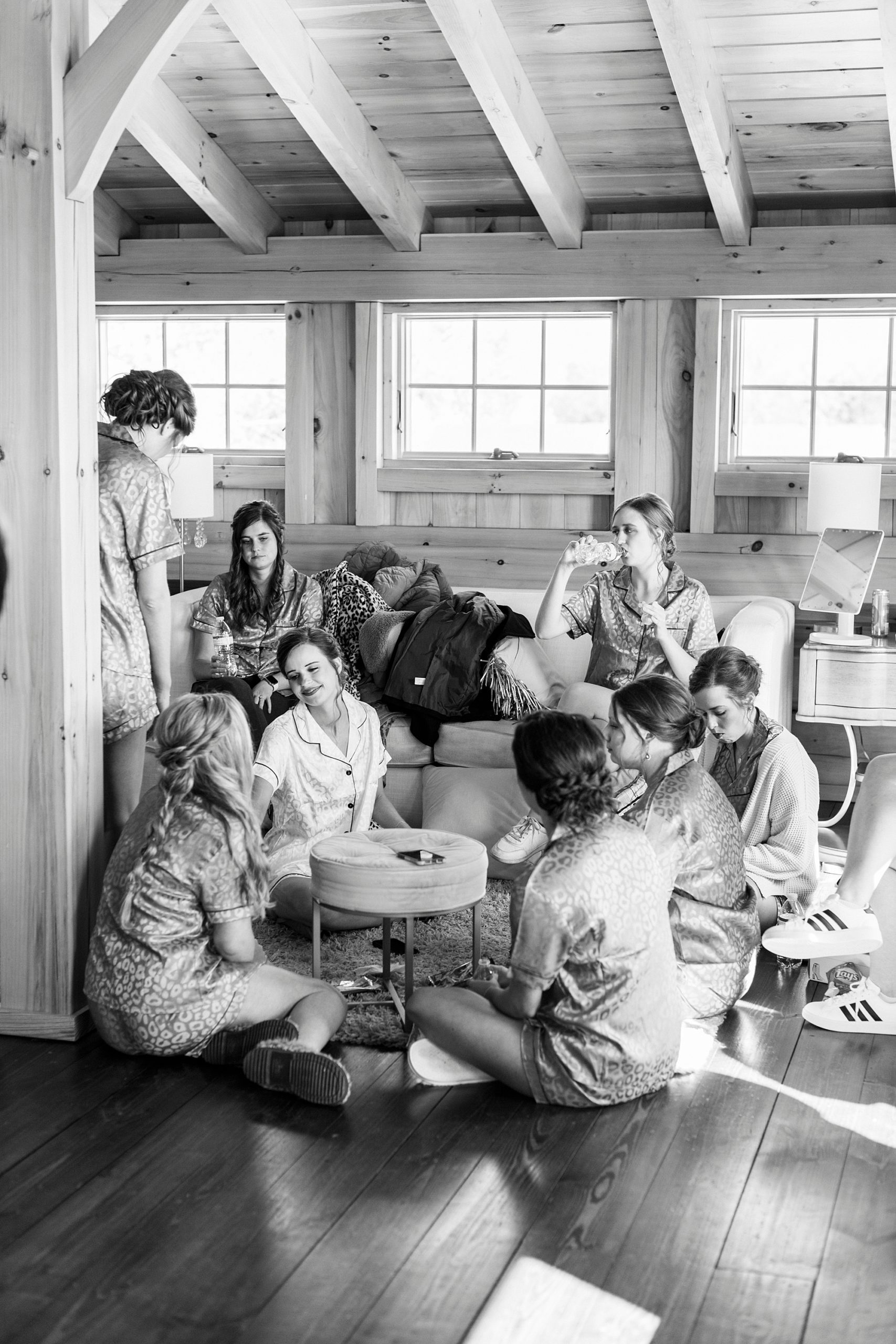 bride and bridesmaids sit together talking before NC wedding 