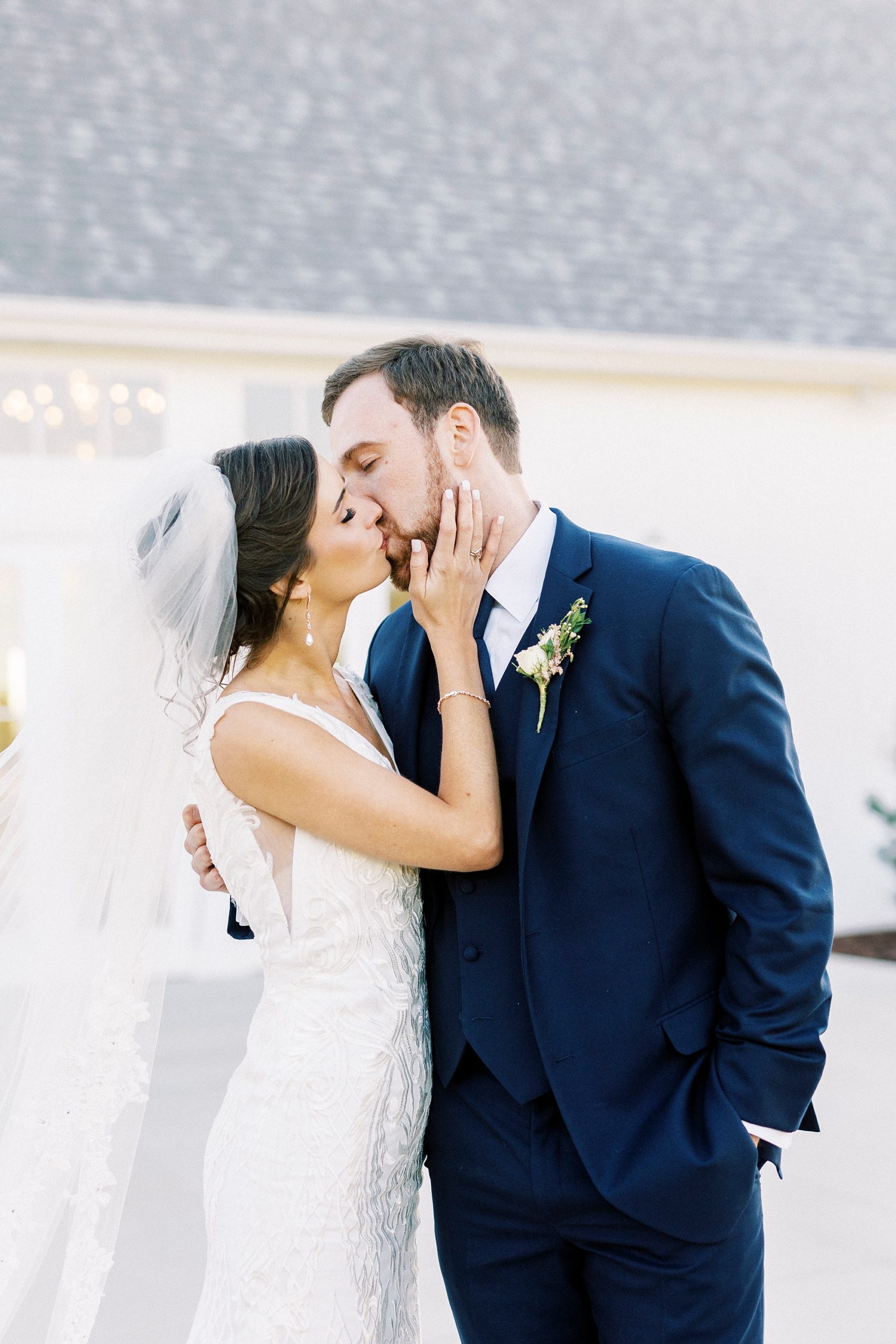 newlyweds kiss outside white barn at Chickadee Hill Farms