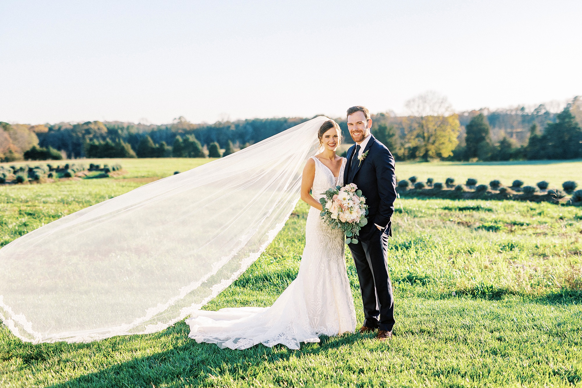 newlyweds stand hugging with bride's veil floating next to them