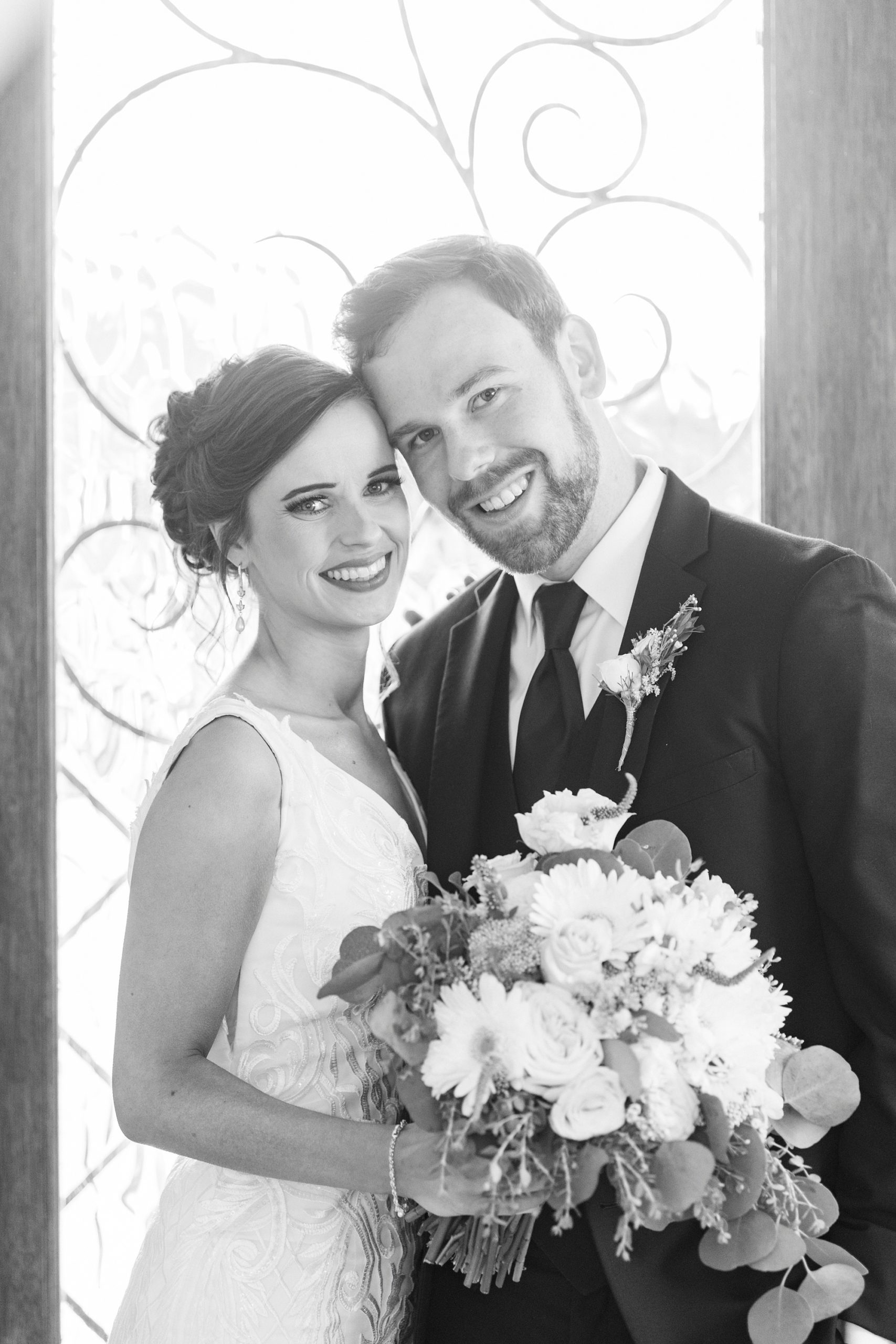 newlyweds stand with heads touching by window at Chickadee Hill Farms