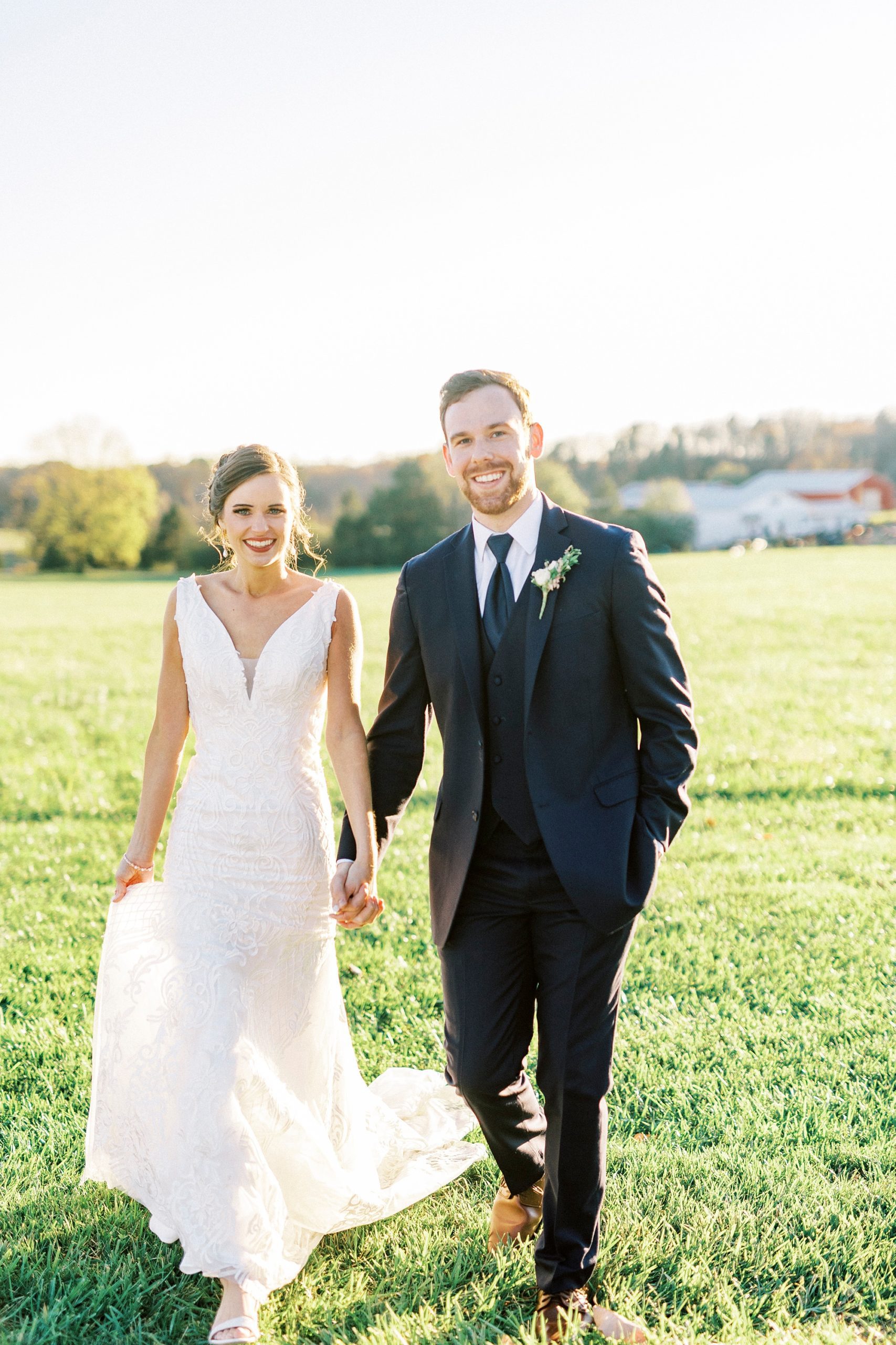 bride and groom hold hands walking on lawn 