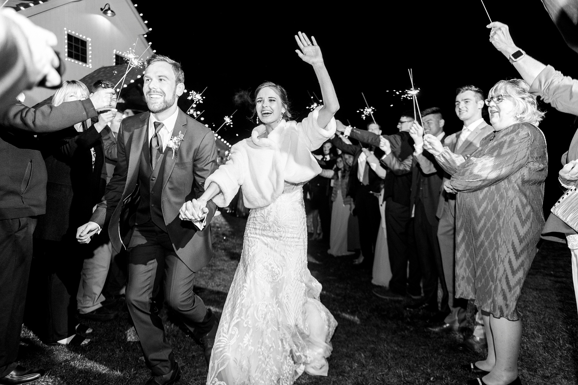 bride and groom wave at guests walking through sparkler exit 