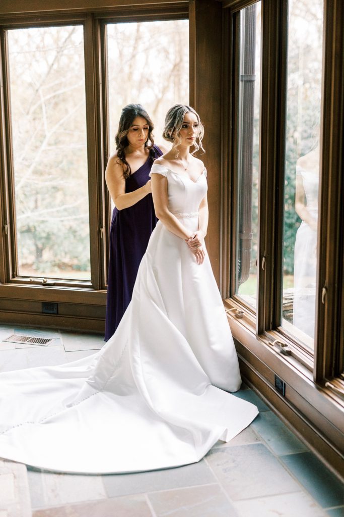 mother helps bride into wedding gown