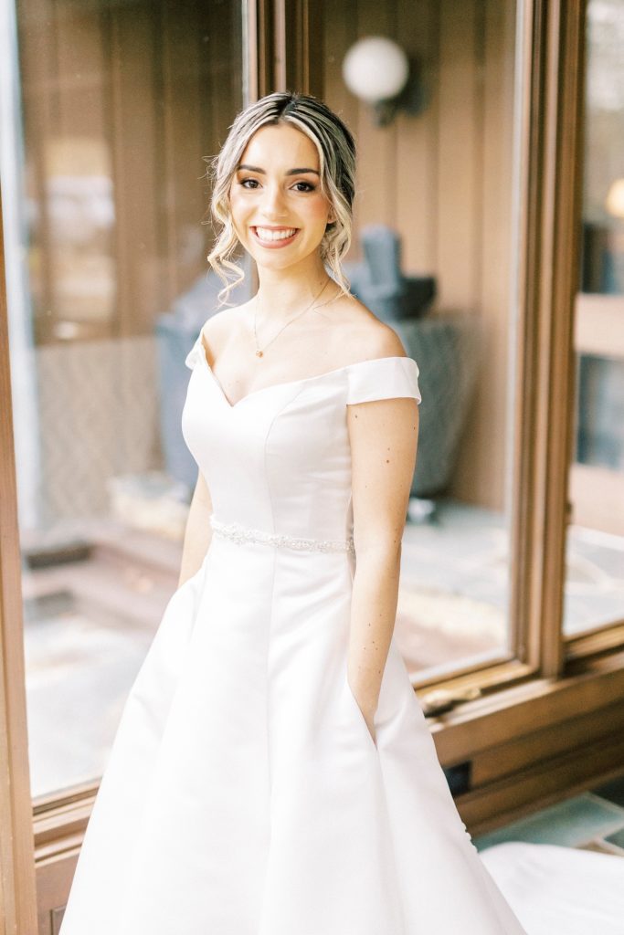 bride smiles standing in wedding gown with pockets 