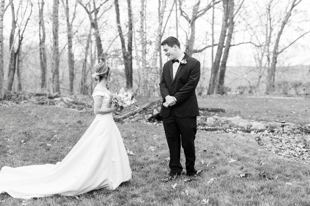 bride approaches groom for first look on lawn 