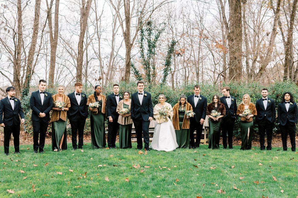 bride and groom smile at each other walking with bridal party 
