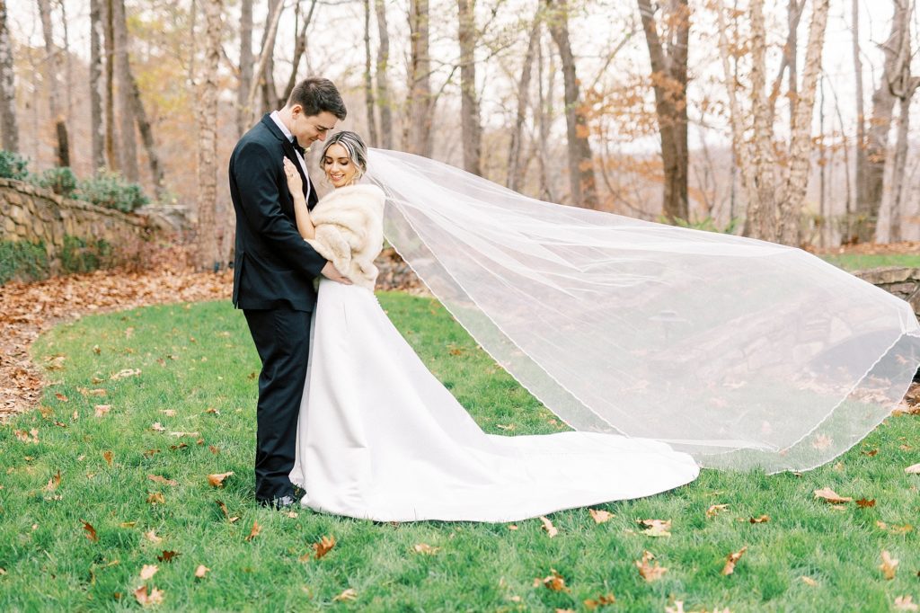 groom looks down at bride with her veil floating behind them 