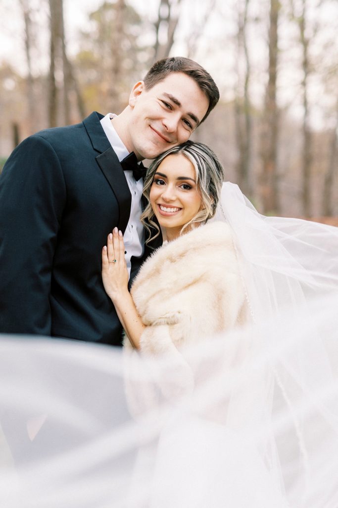 bride leans head on groom's chest with veil around them 