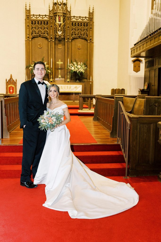 newlyweds hug on red carpet in St. James Lutheran Church in Concord NC