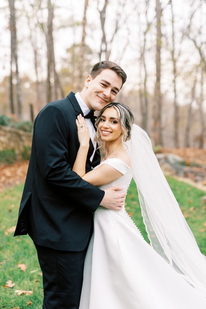 bride leans against groom's chest hugging him 