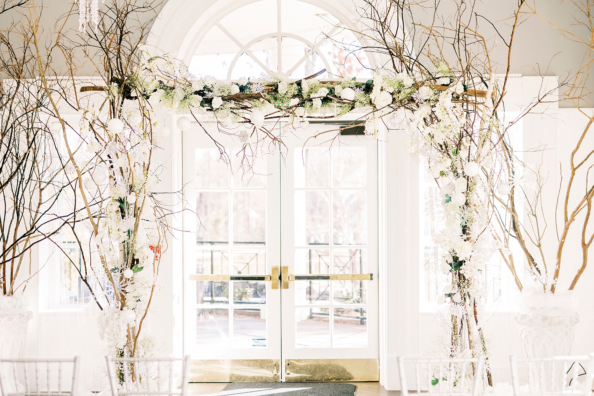 ceremony inside River Run Country Club with white florals and branches