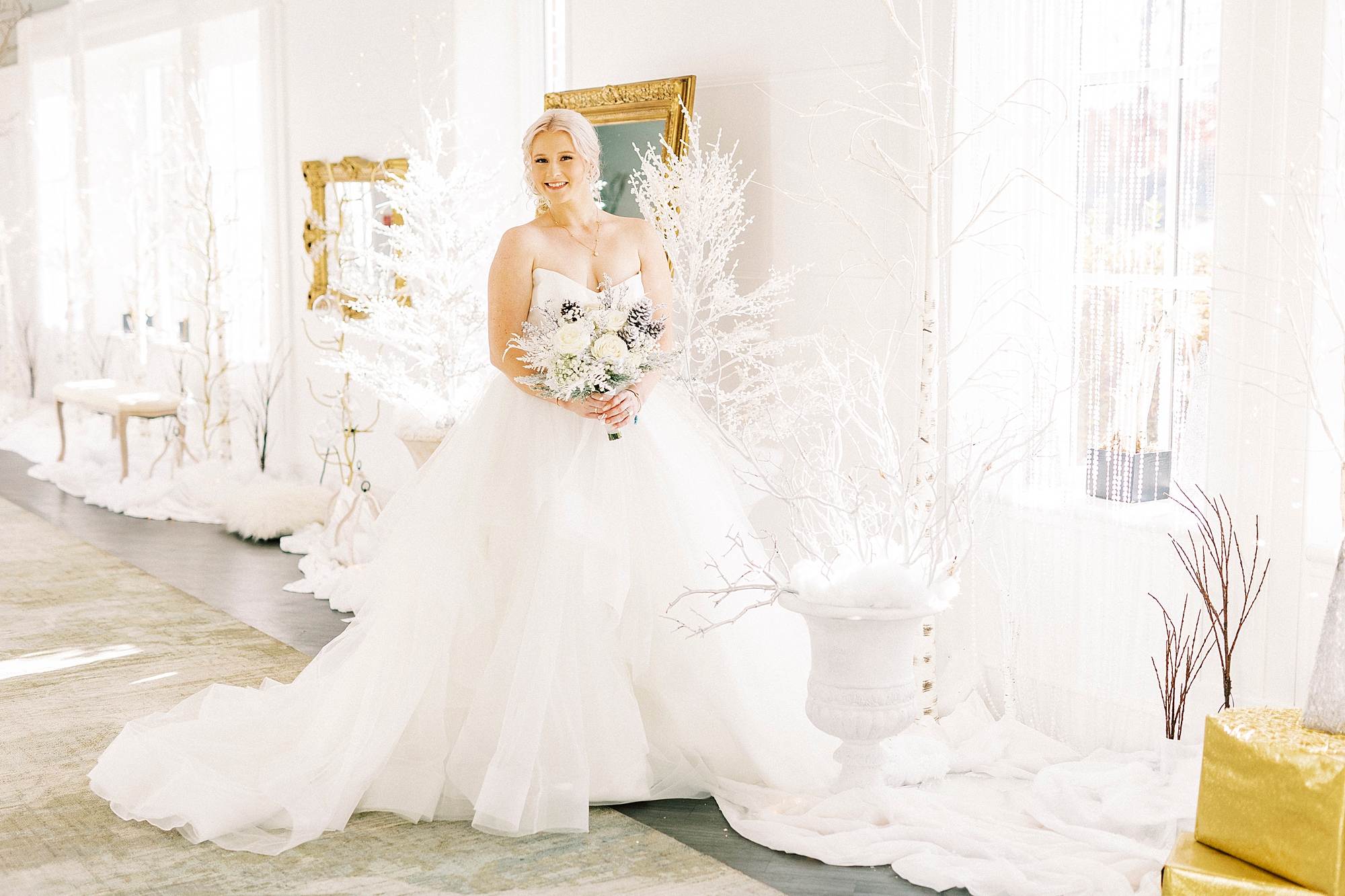 bride in strapless gown poses among white floral display