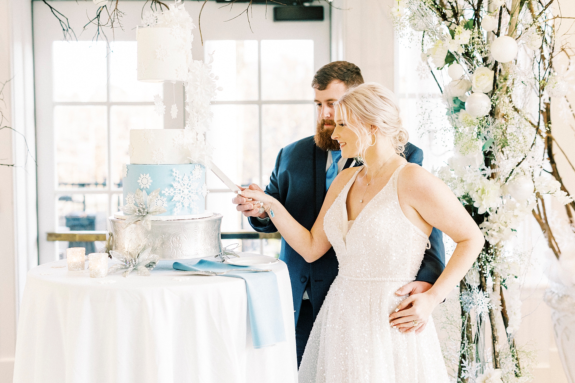 newlyweds cut wedding cake during Winter Wonderland wedding at River Run Country Club