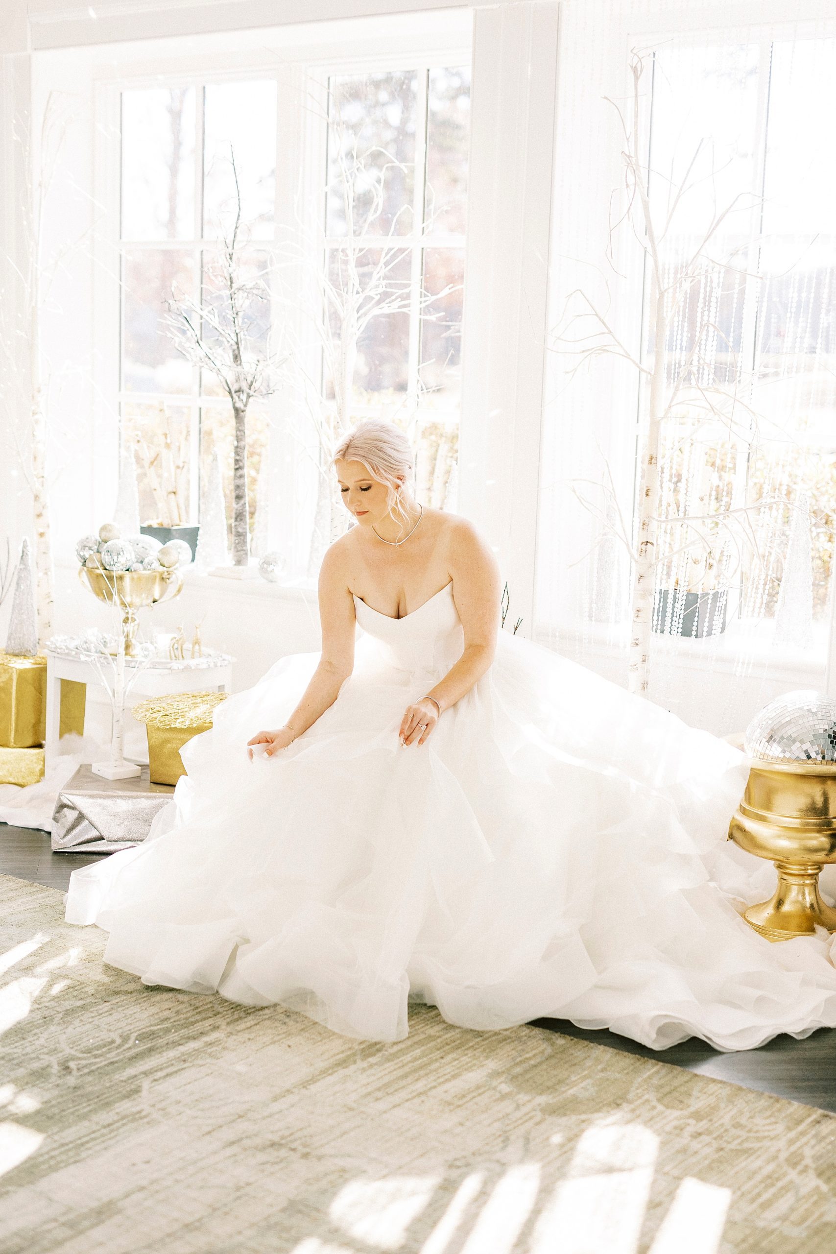 bride adjusts skirt of wedding gown in seating area