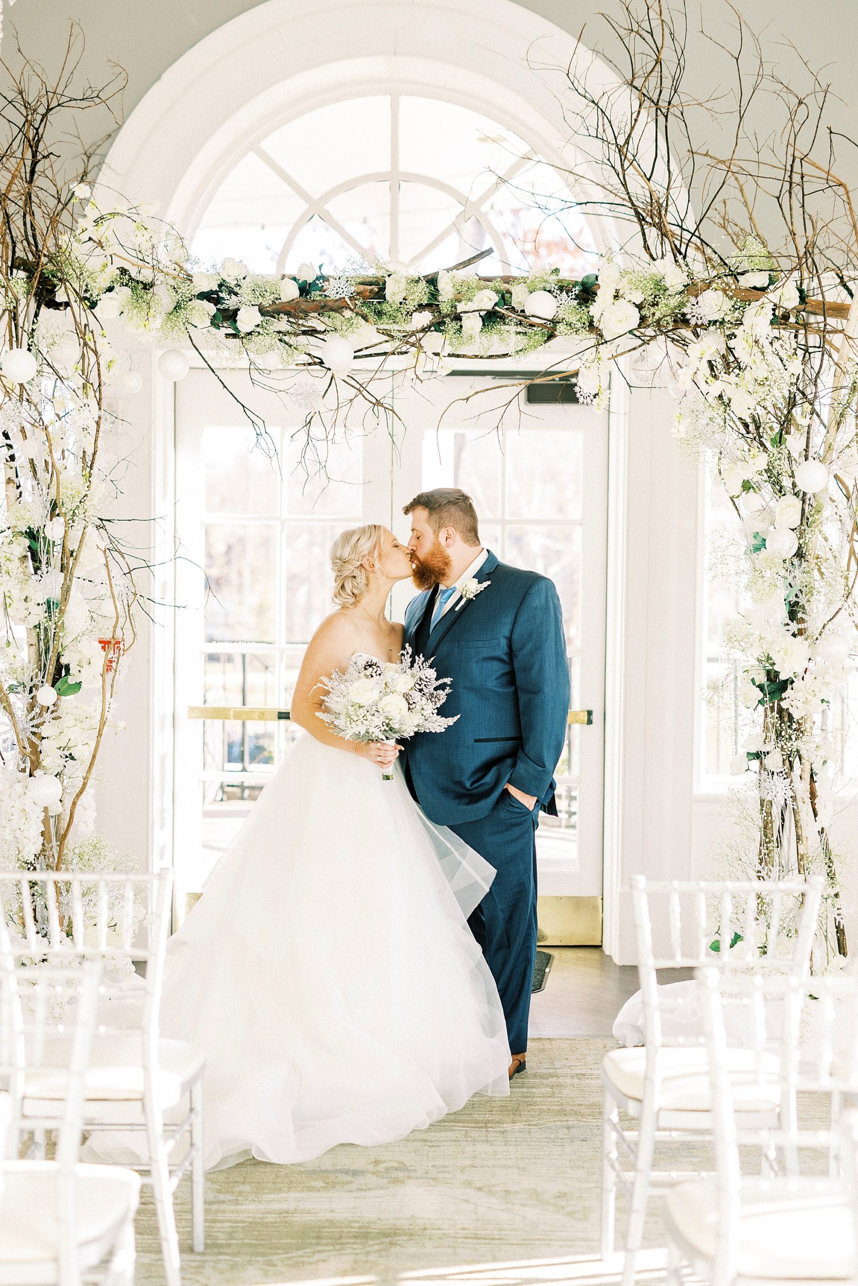 groom kisses bride under winter arbor in River Run Country Club