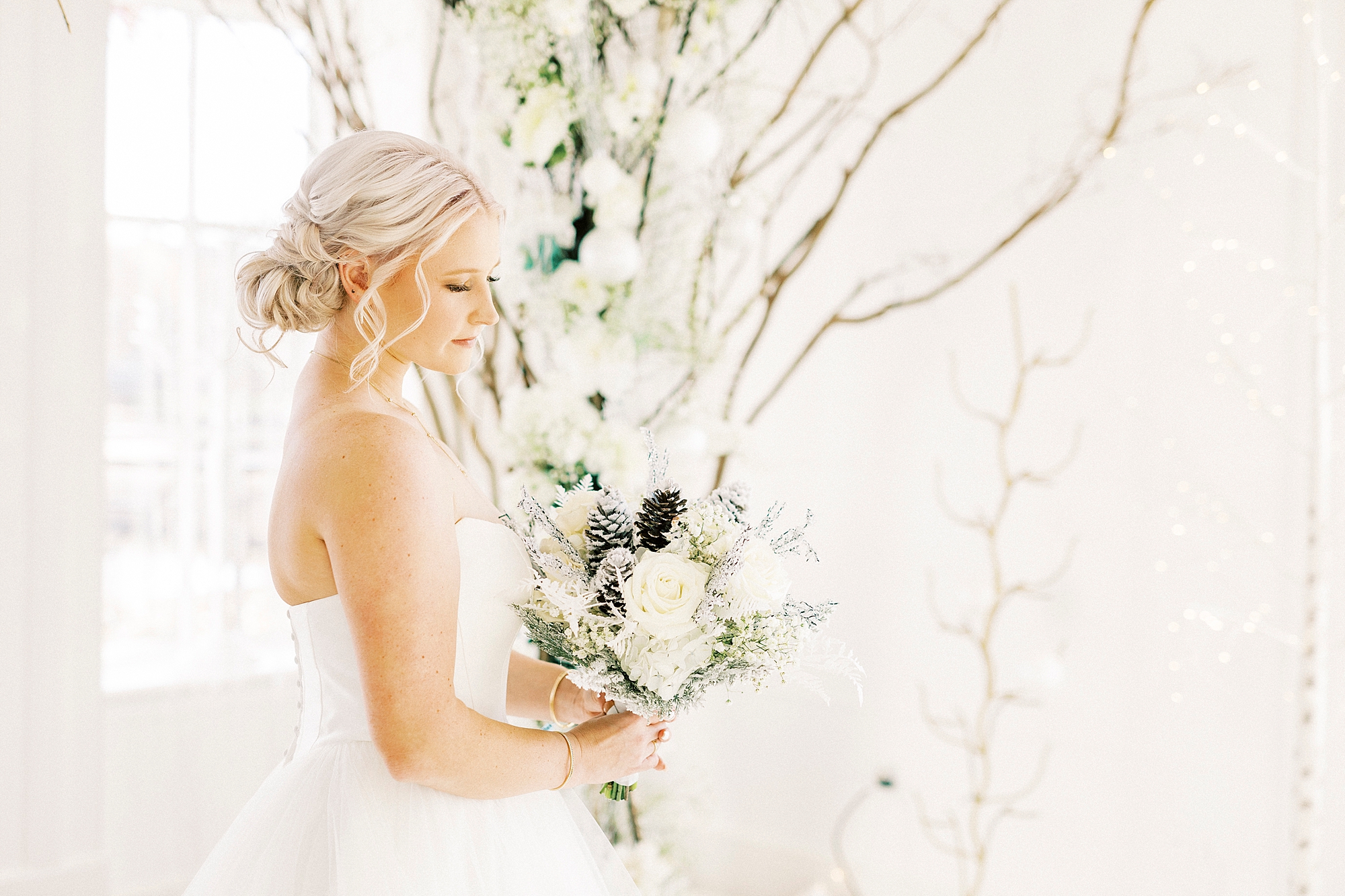 bride poses with bouquet by tree inside River Run Country Club