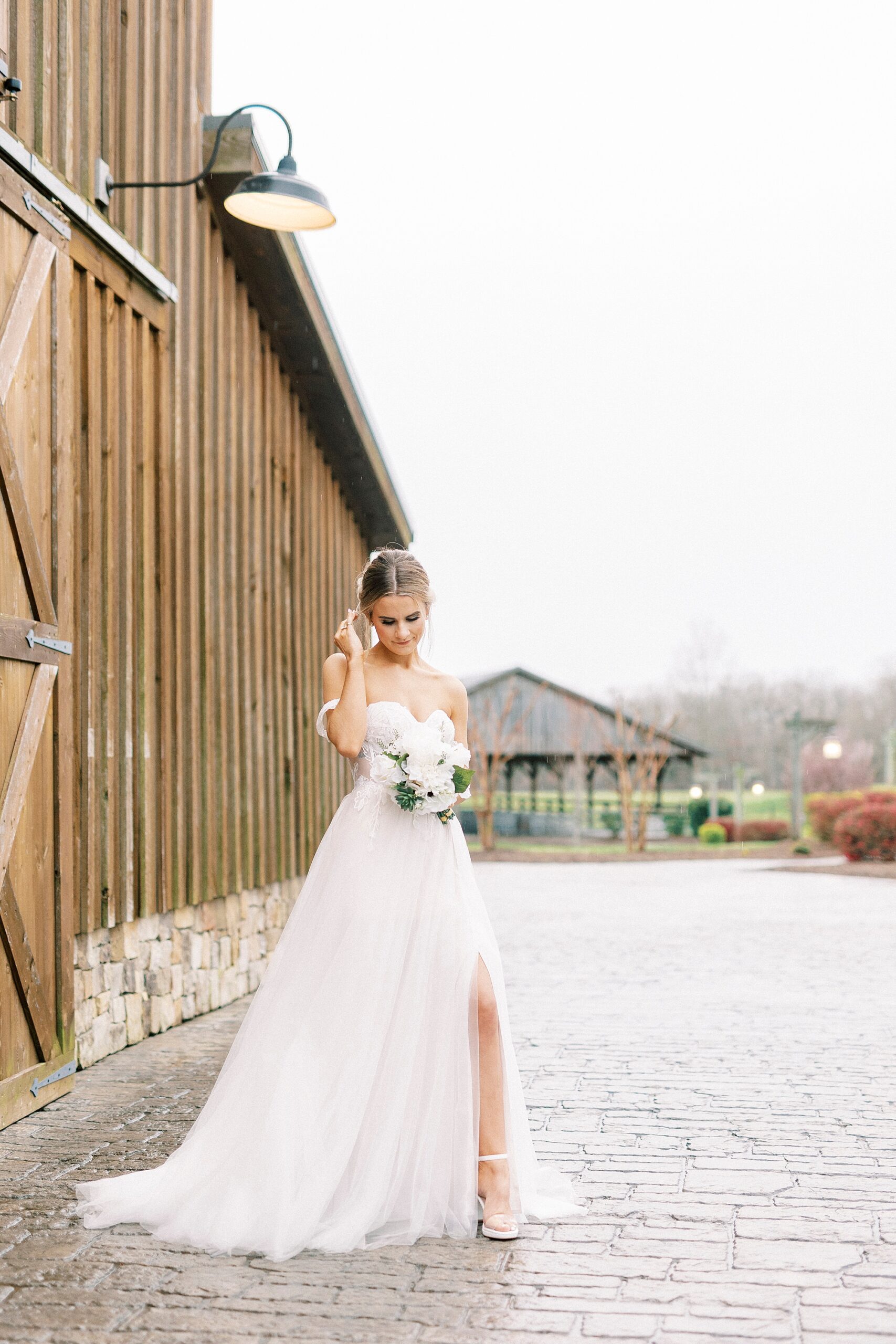 bride pushes hair over ear with leg peeking out of slit in wedding gown 
