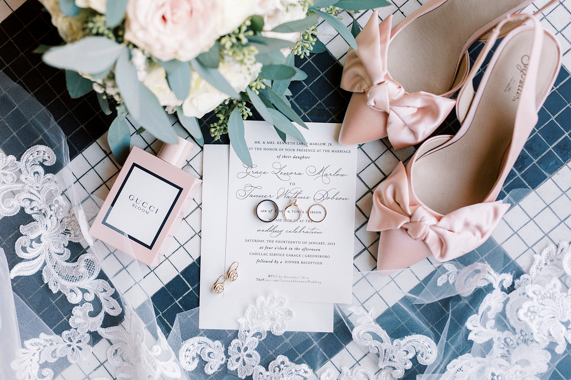 wedding invitation rests on black and white floor with bride's pink shoes 
