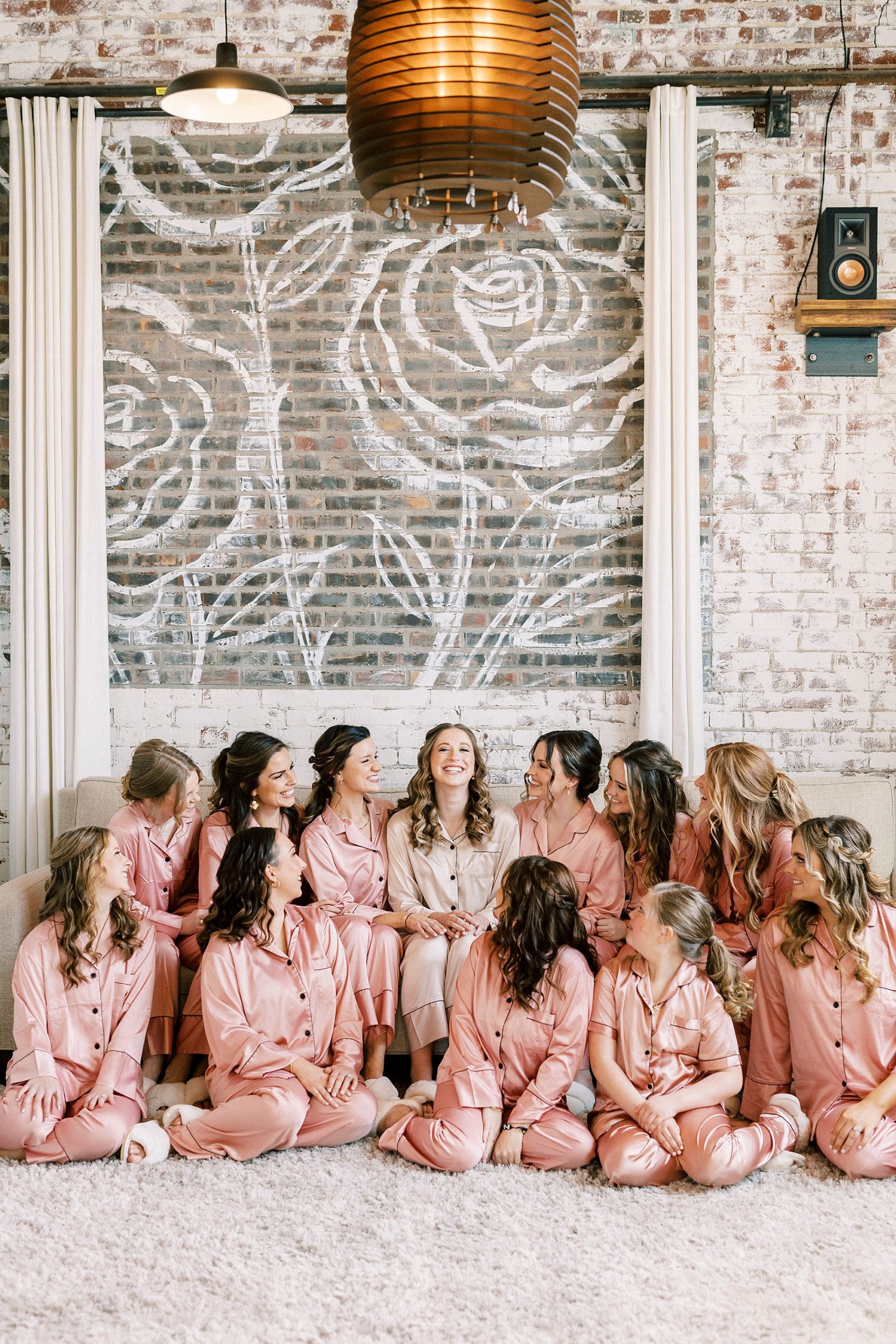 bride sits with bridesmaids in matching pink robes 