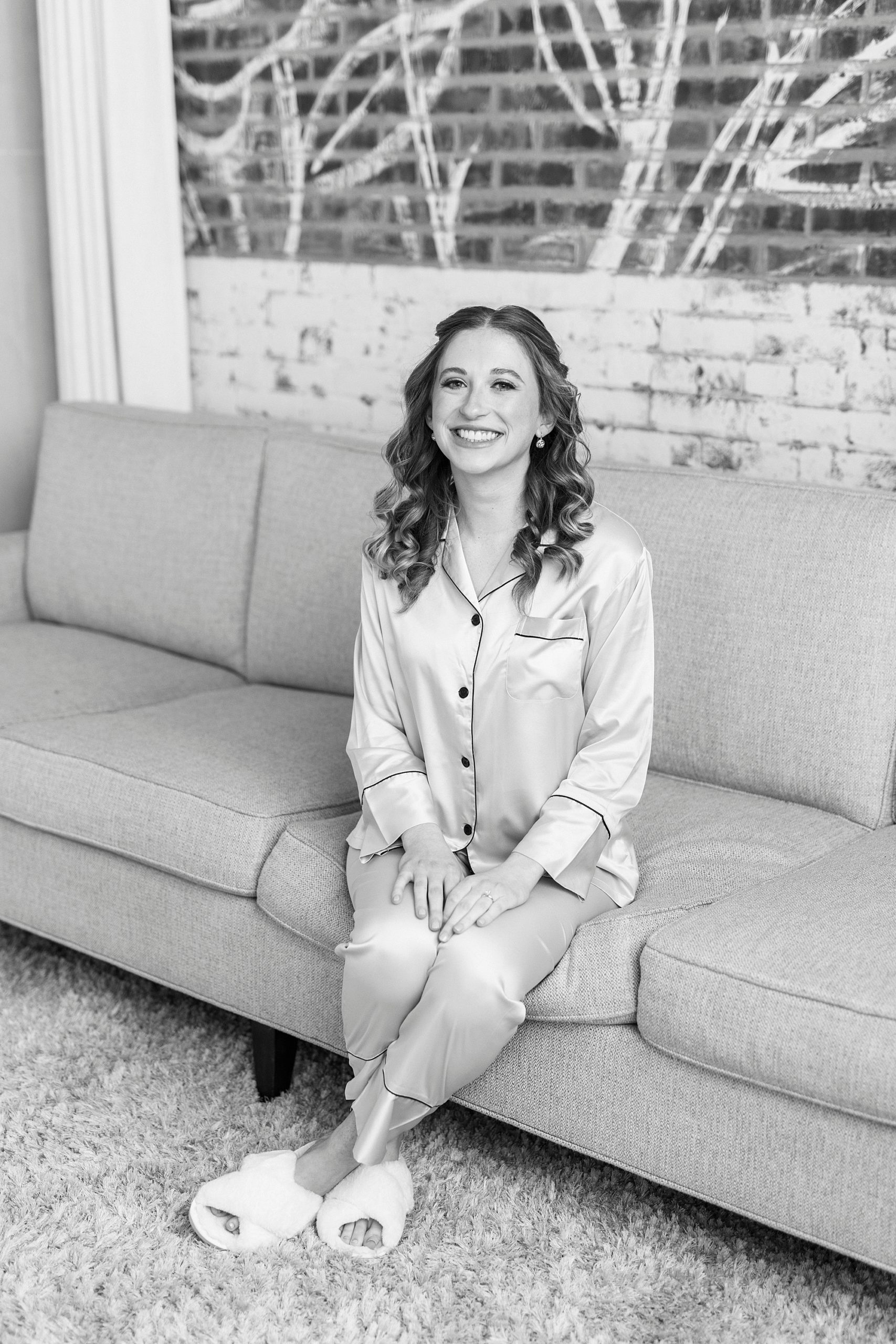bride in silk pajamas sits on couch at the Cadillac Service Garage 