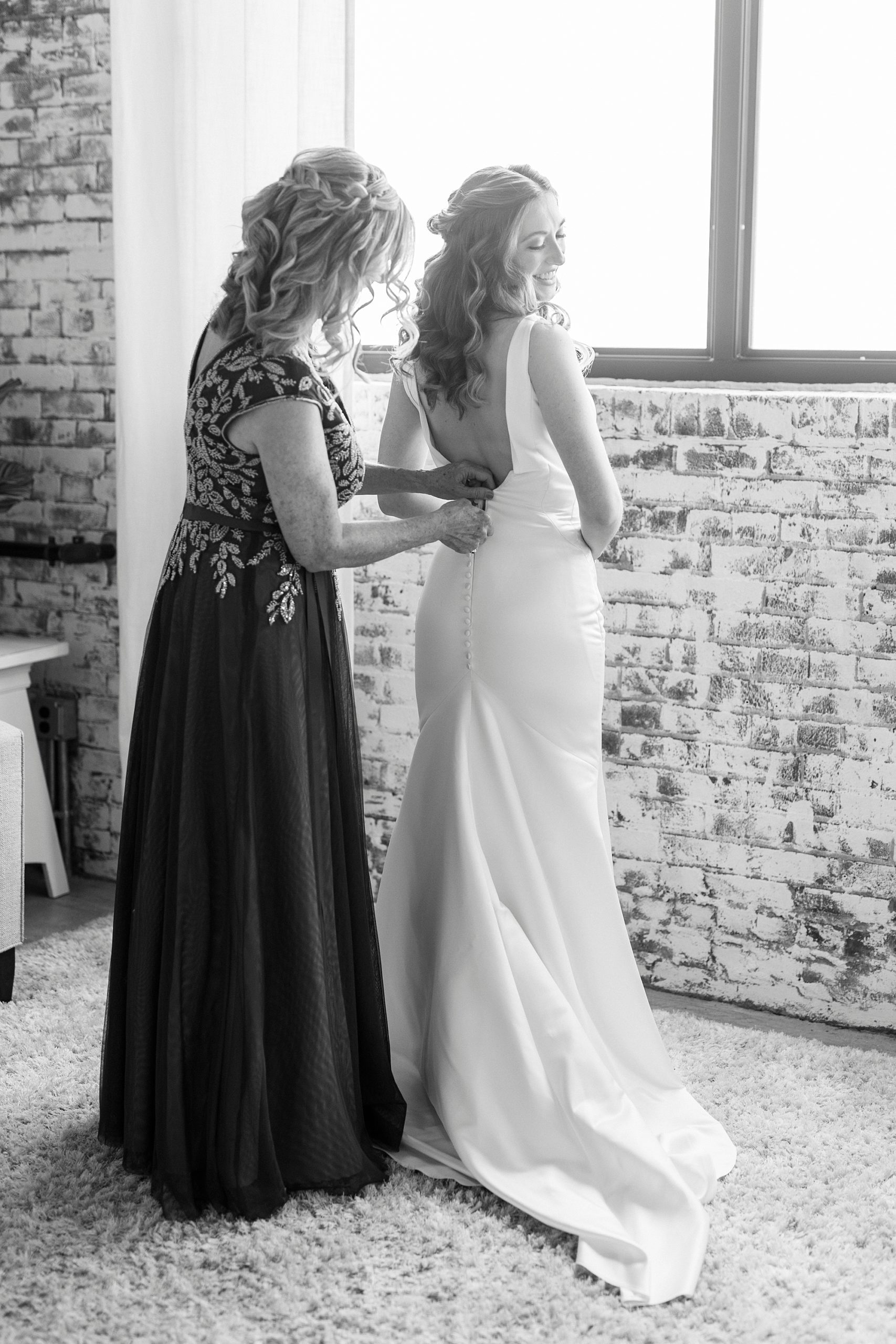 bride gets into wedding dress with mother at the Cadillac Service Garage