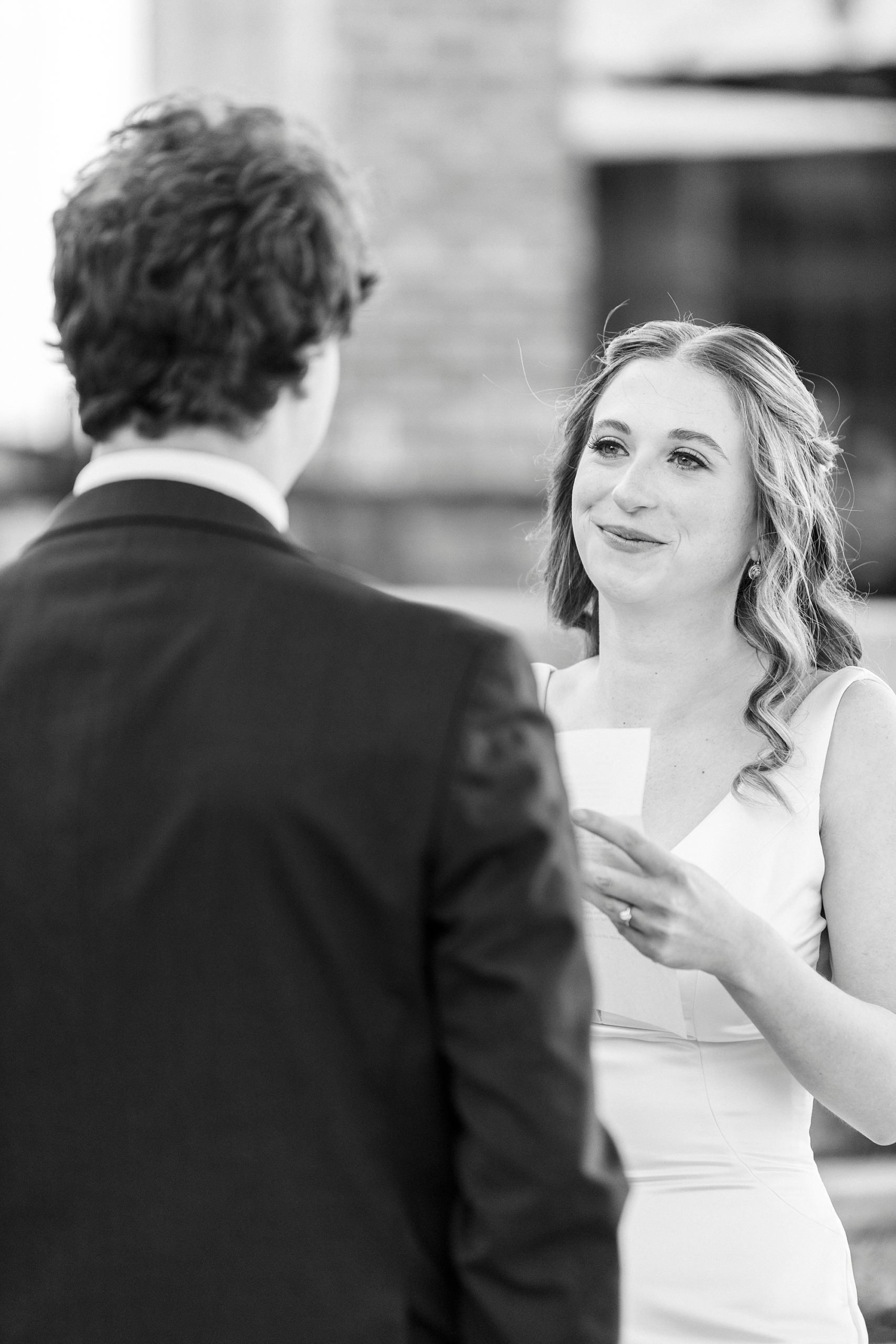 bride reads groom a letter during their first look outside the Cadillac Service Garage