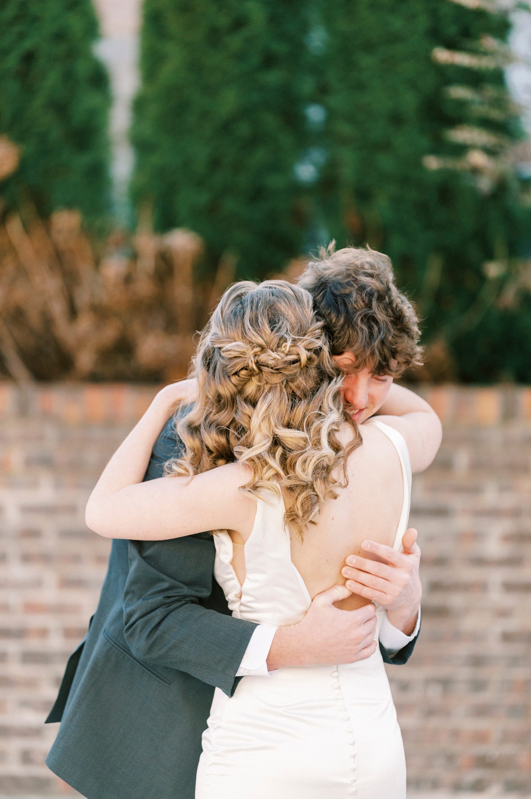 bride and groom hug on wedding day during first look 