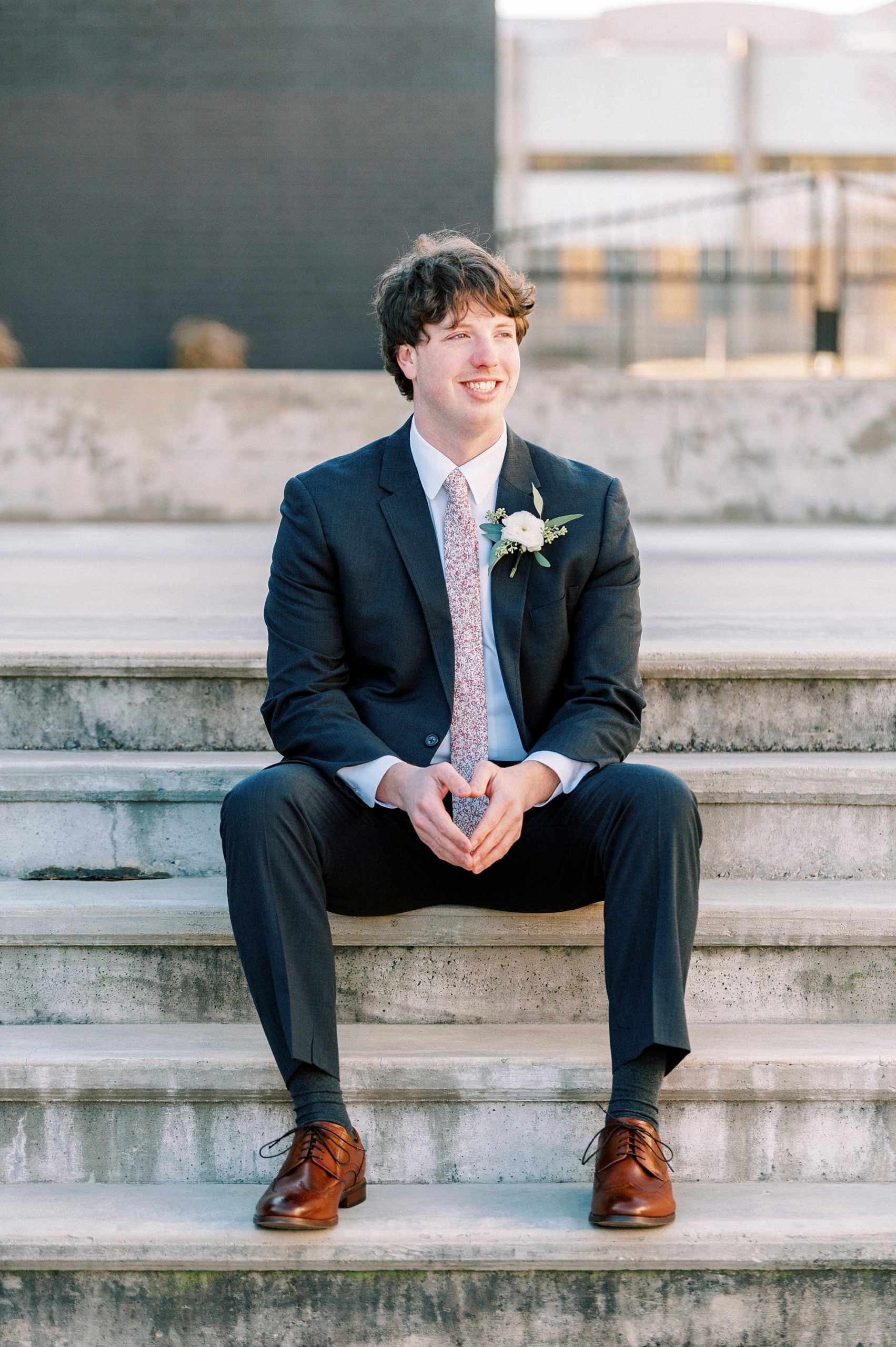 groom sits on stone steps outside the Cadillac Service Garage