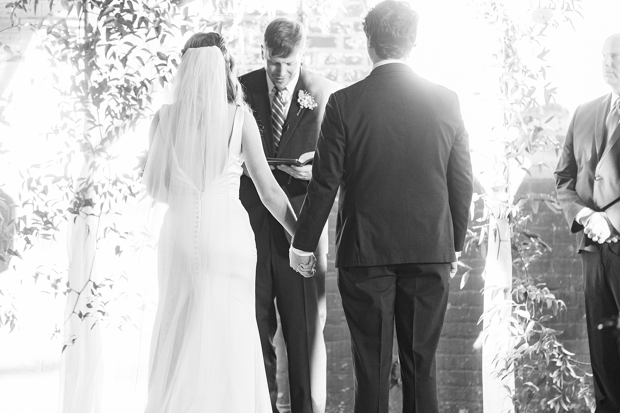 newlyweds hold hands during Christ-centered wedding ceremony at the Cadillac Service Garage in Greensboro NC