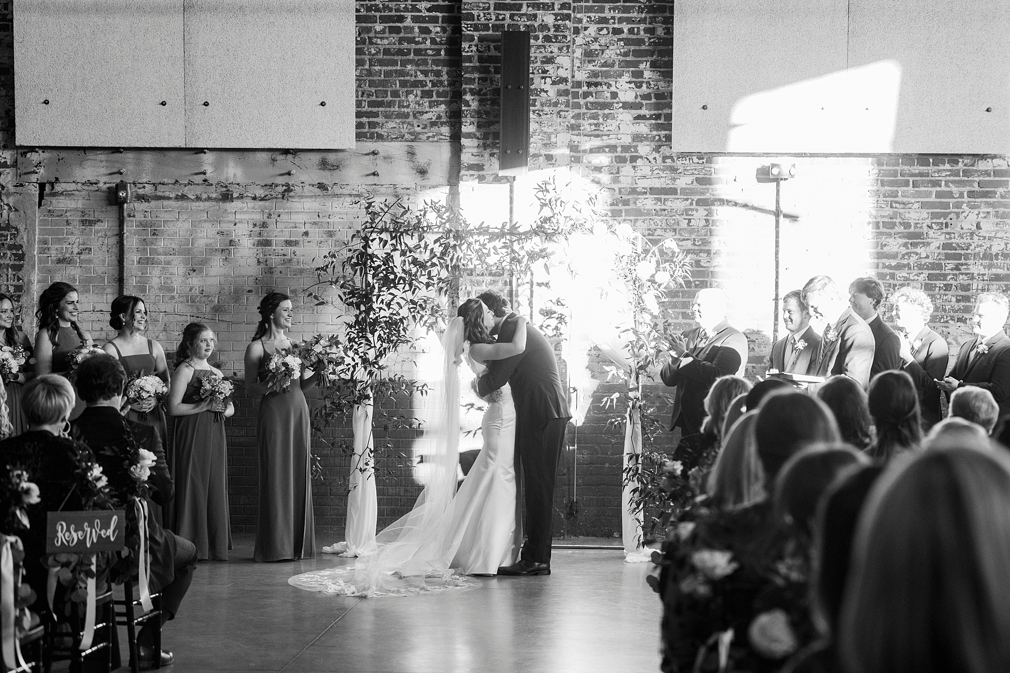 groom dips bride kissing her during Christ-centered wedding ceremony at the Cadillac Service Garage in Greensboro NC