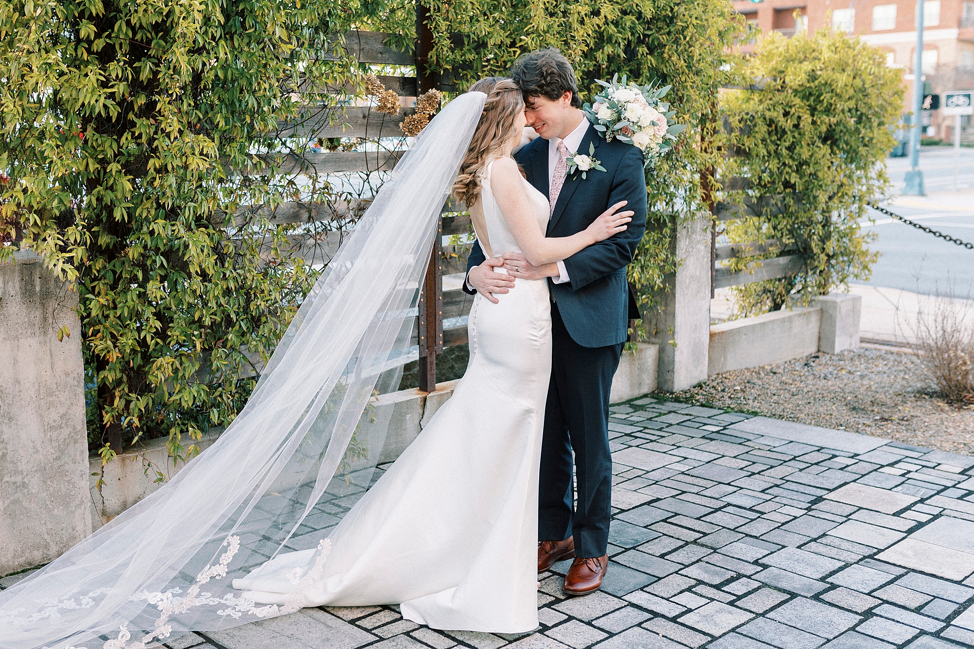 bride and groom hug on patio at the Cadillac Service Garage with foreheads touching 