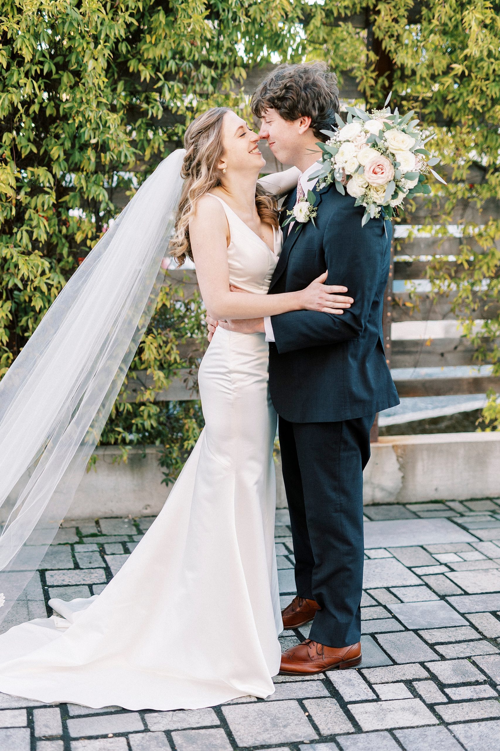 bride and groom smile touching noses during portraits on patio at the Cadillac Service Garage