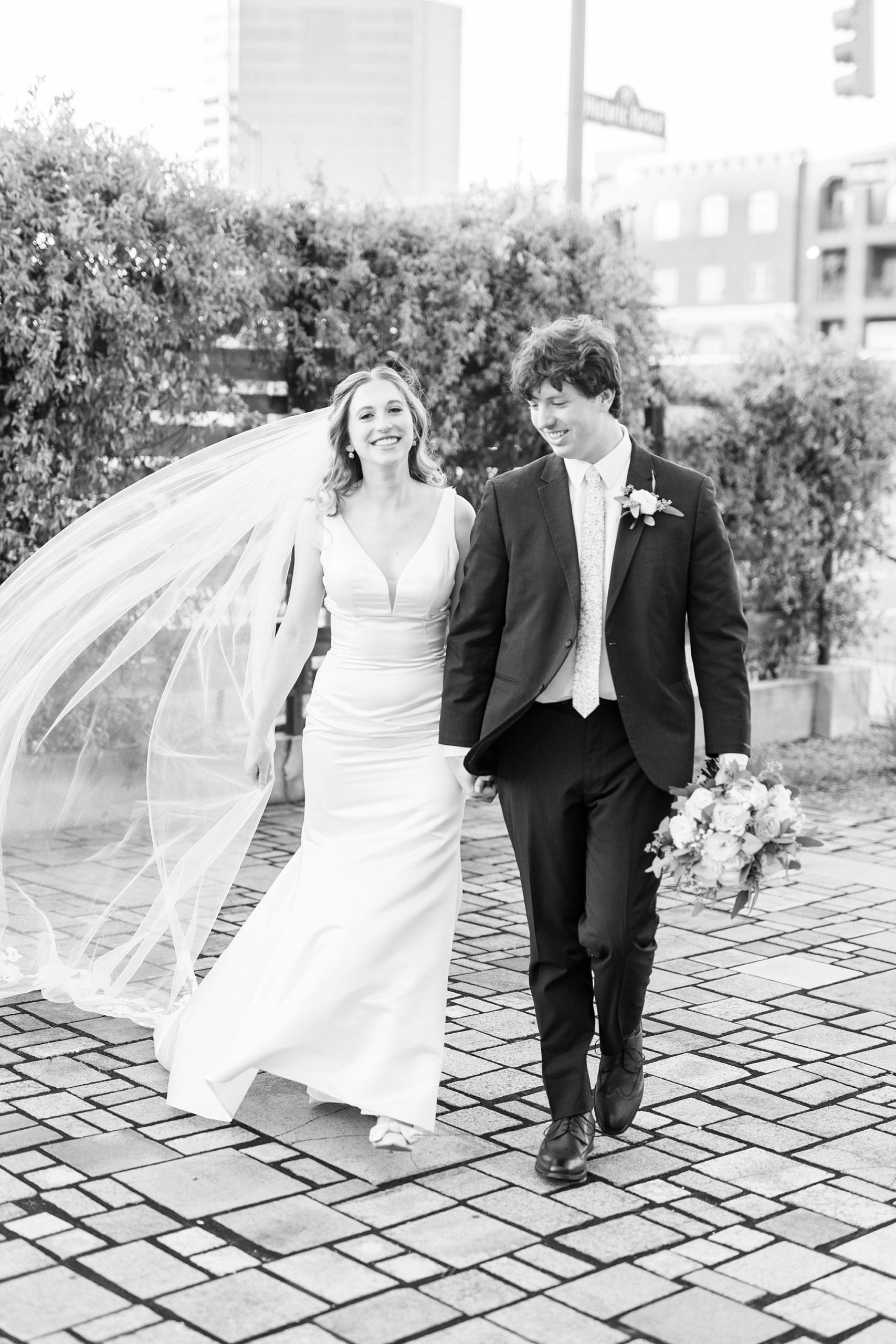 bride and groom hold hands walking on brick patio at the Cadillac Service Garage