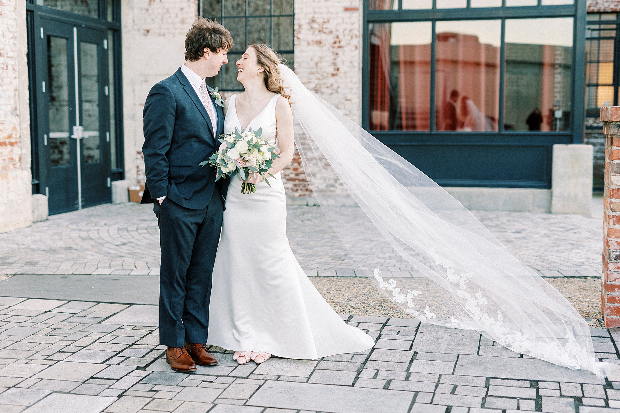 bride smiles up at groom during portraits on patio at the Cadillac Service Garage