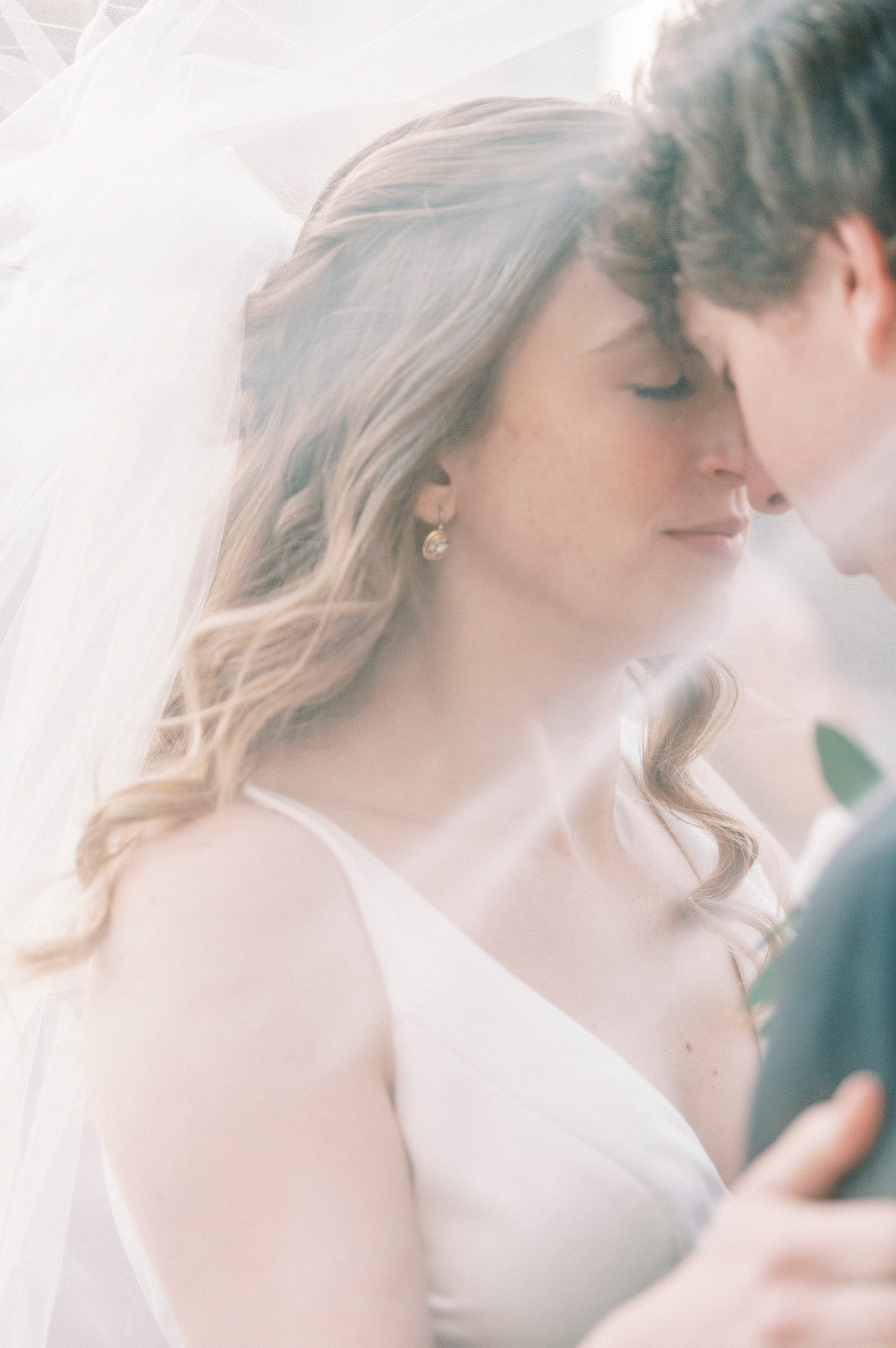 bride and groom lean heads together under bride's veil 