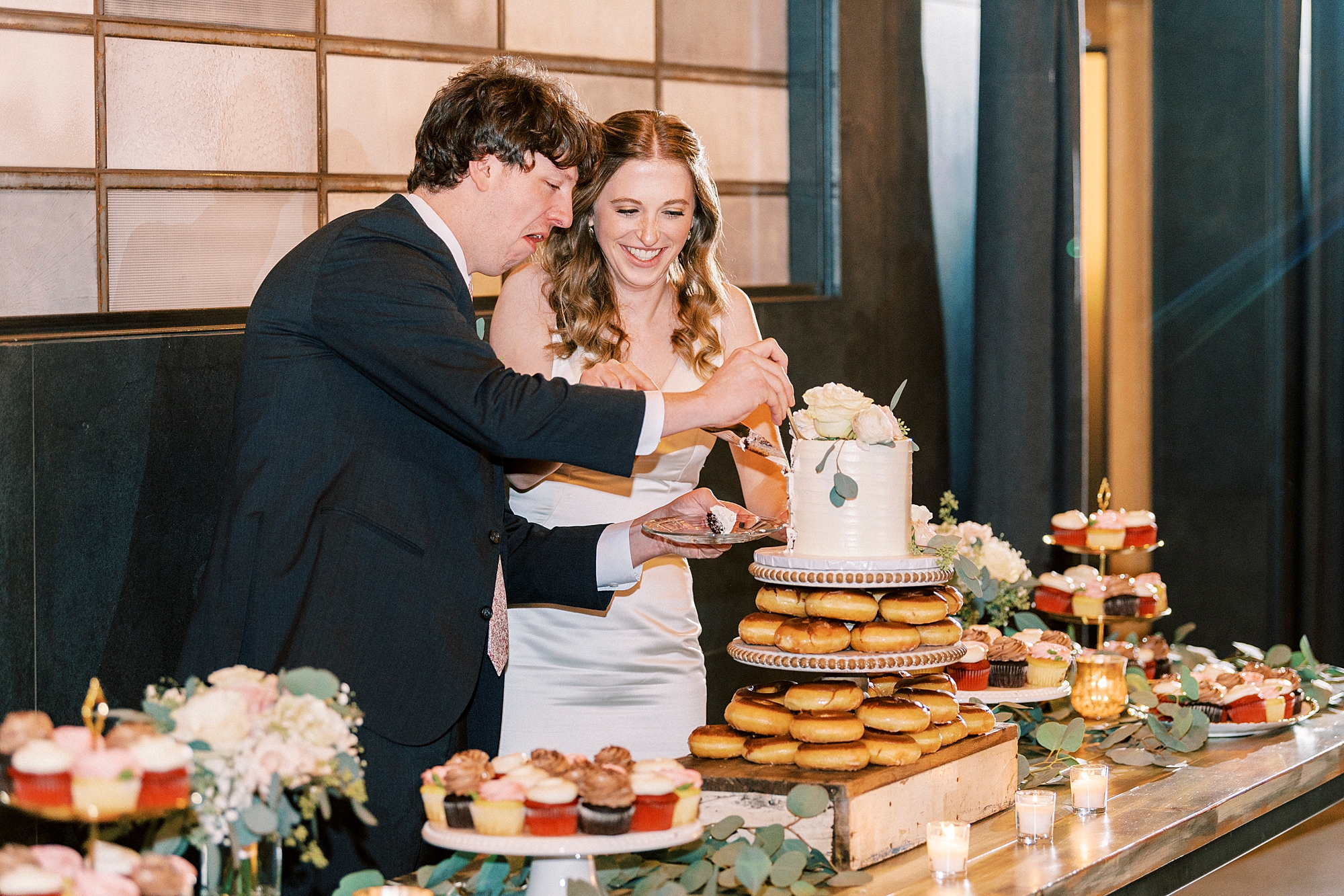 newlyweds cut wedding cake on dessert table 