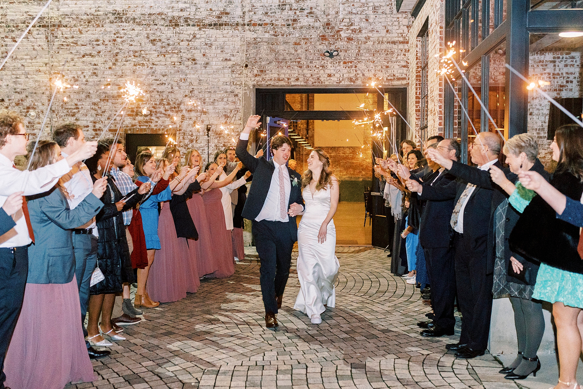 newlyweds laugh leaving the Cadillac Service Garage during sparkler exit