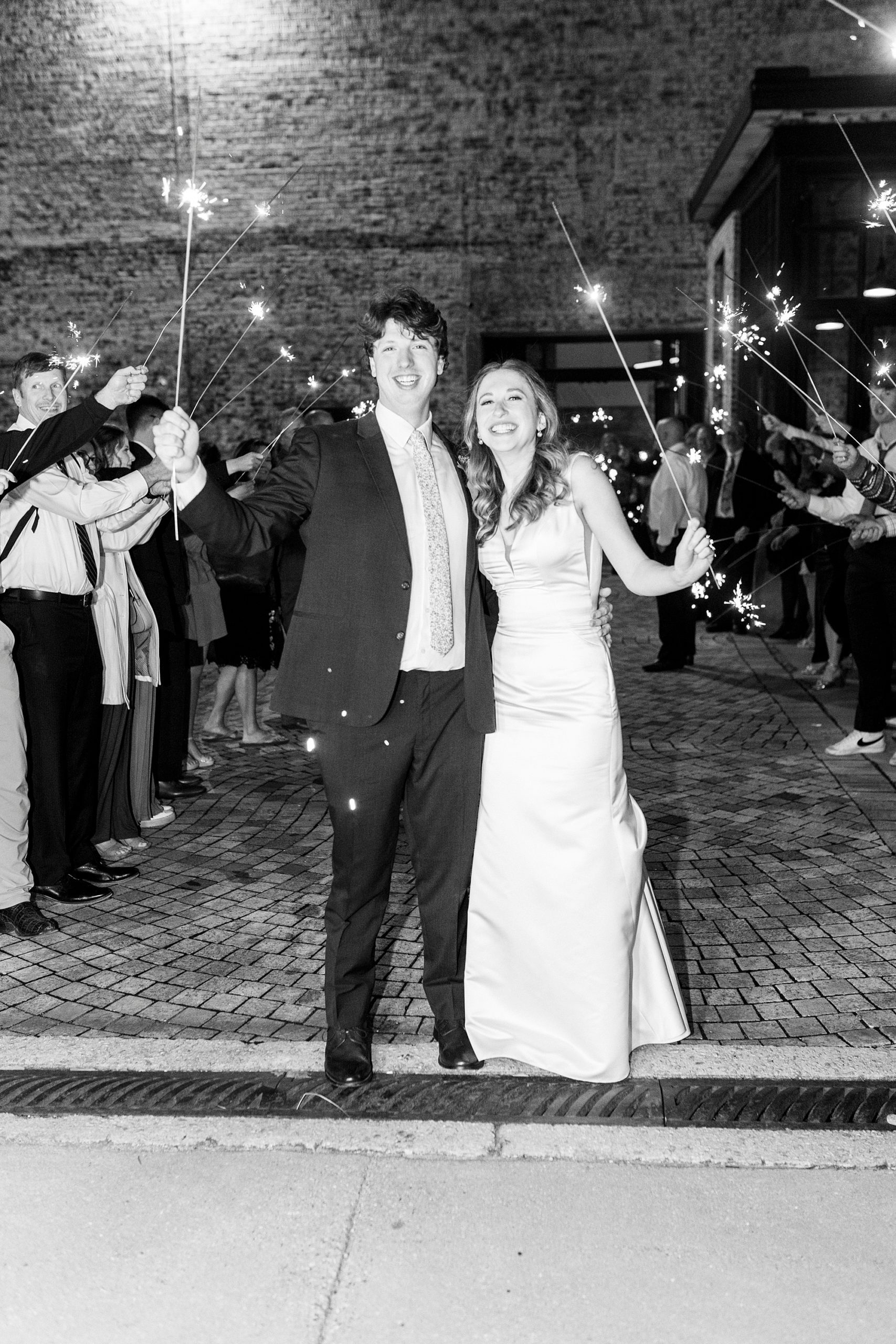 newlyweds laugh leaving the Cadillac Service Garage during sparkler exit